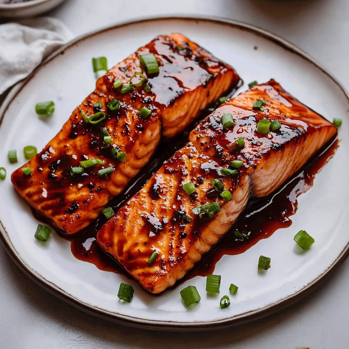 A plate of firecracker salmon with sauce and garnished with green onions.