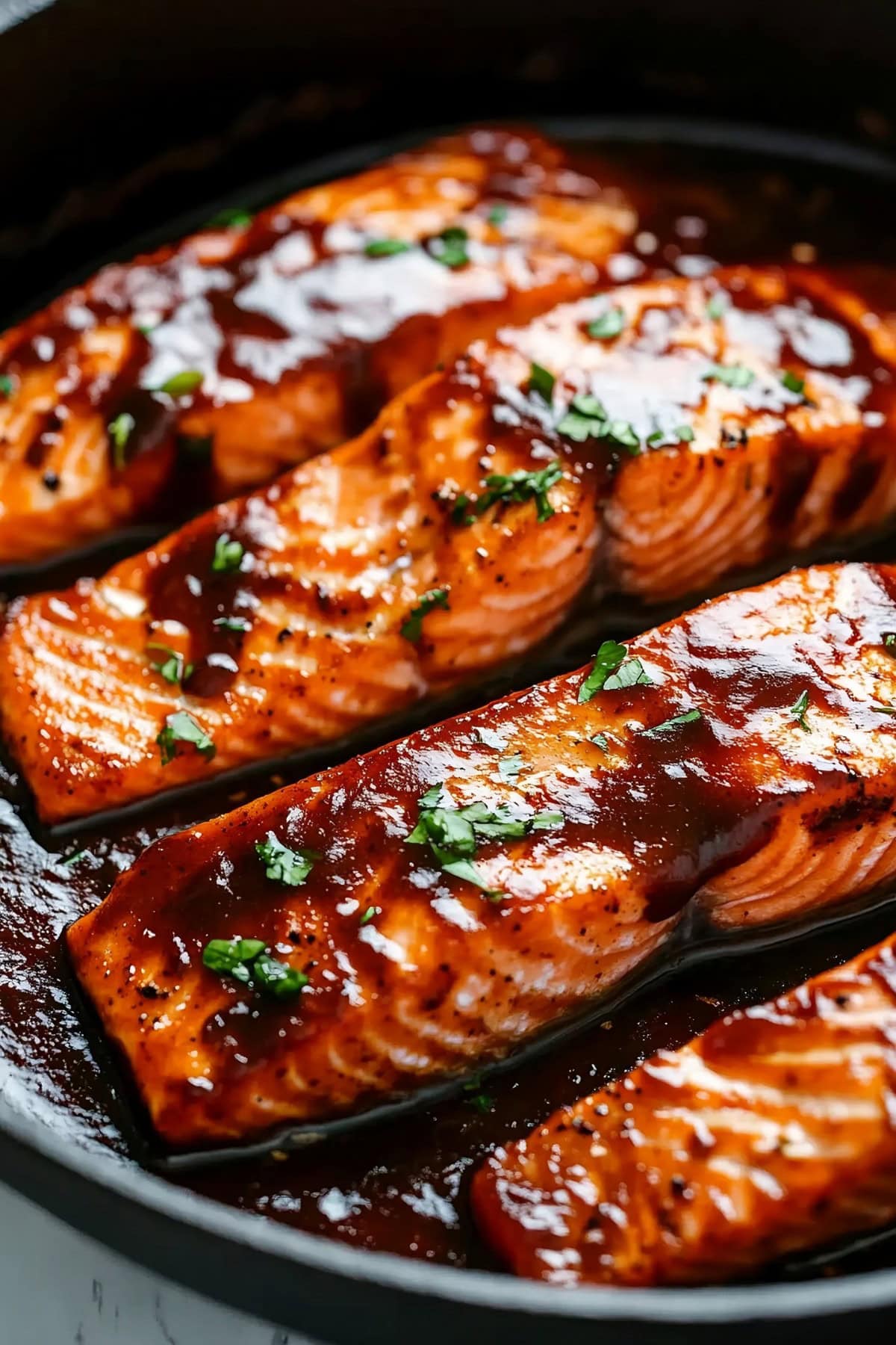 Firecracker salmon with herbs in a black skillet.