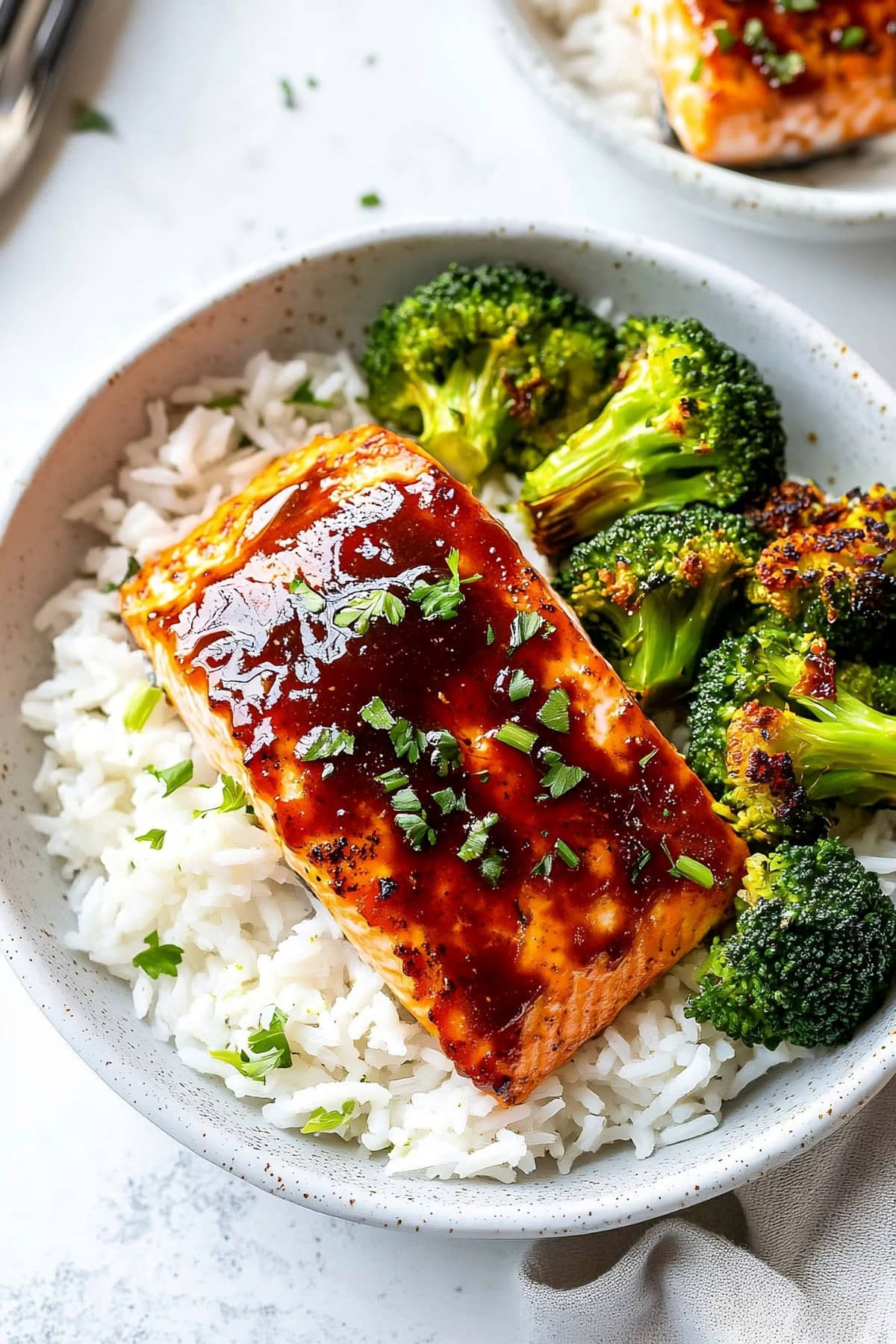 A bowl of firecracker salmon with rice and broccoli.