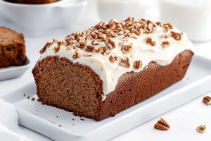 Gingerbread loaf covered with cream cheese and chopped pecans.