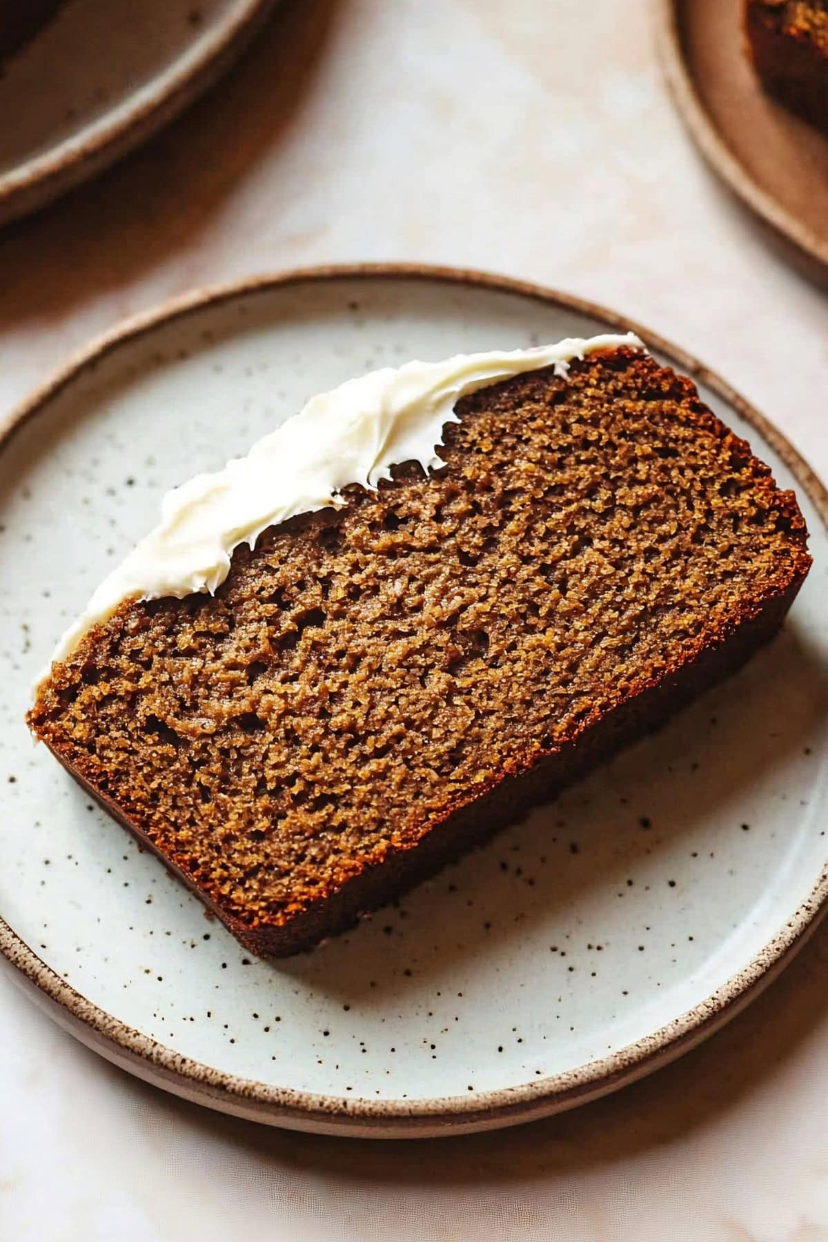 Sliced of gingerbread loaf with cream cheese frosting served on a white plate, top view