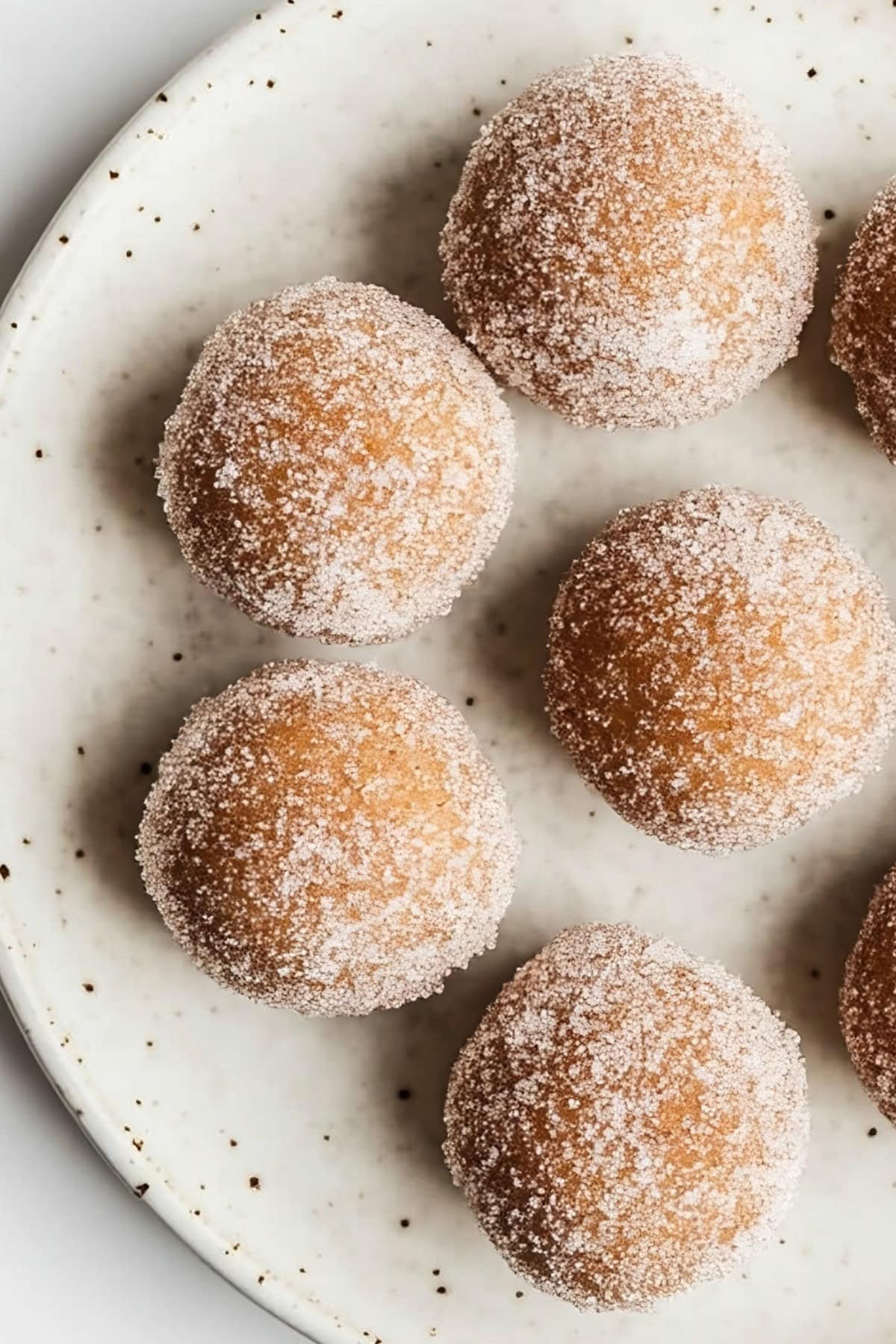 A close-up shot of pumpkin spice donut holes, highlighting their golden crust and cinnamon-sugar coating, top view