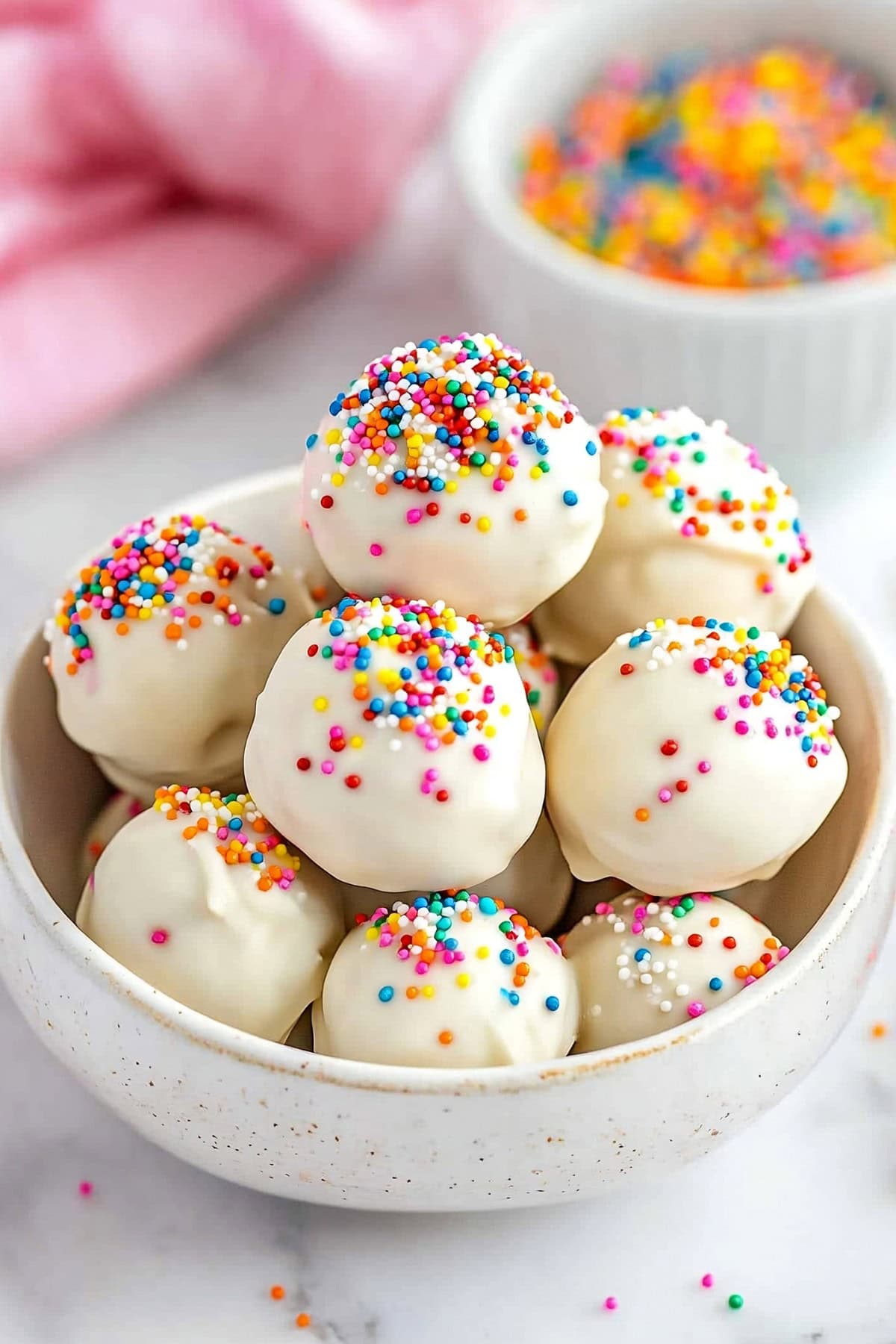 Sugar cookie truffles with candy sprinkles piled in a white bowl