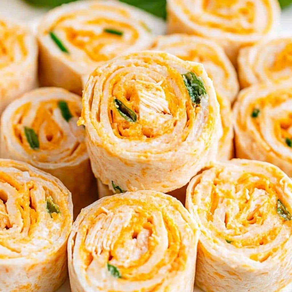 Platter full of shredded buffalo chicken filled tortilla roll-ups, close up