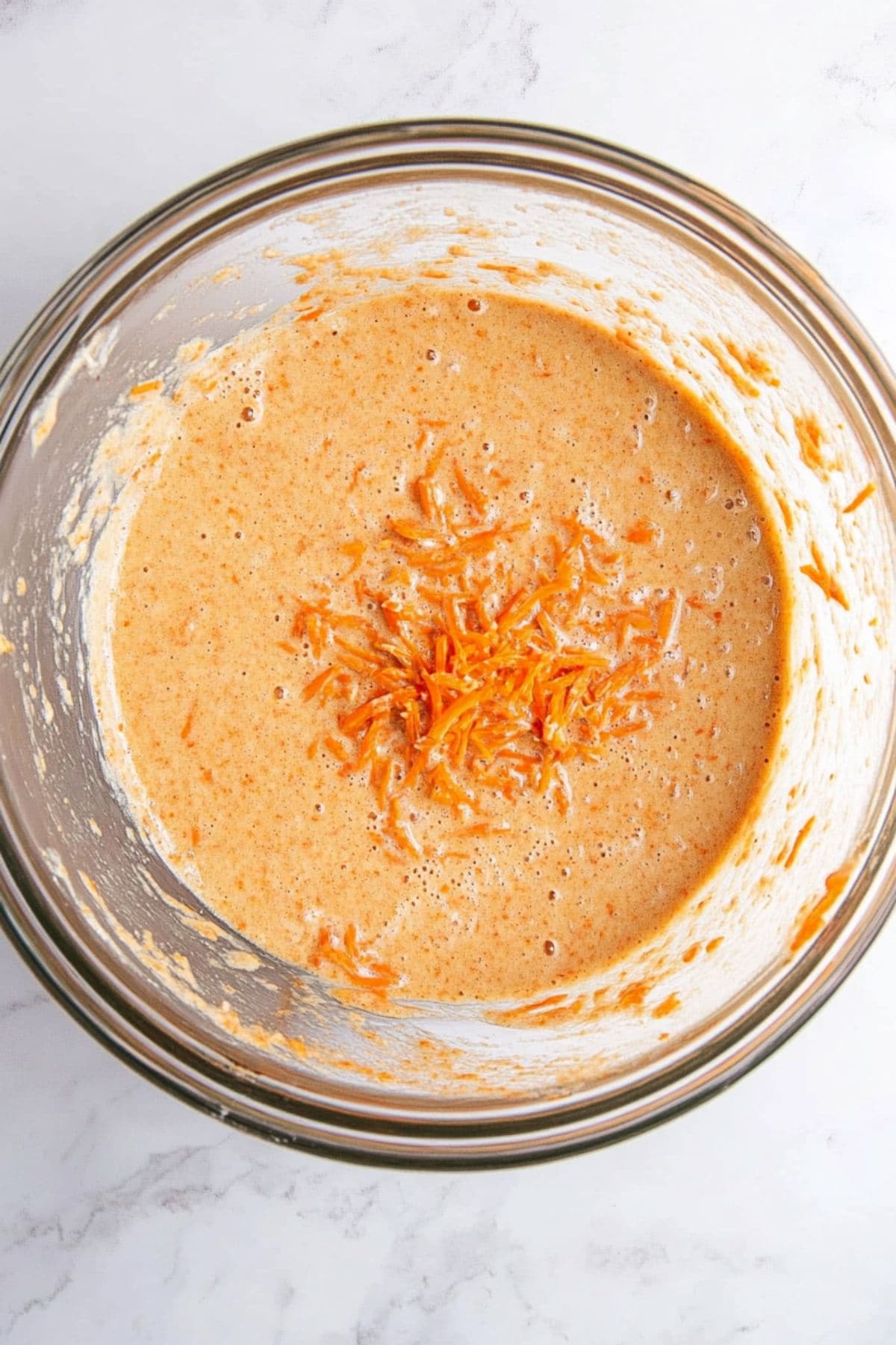 Carrot cake batter in a glass mixing bowl, top view