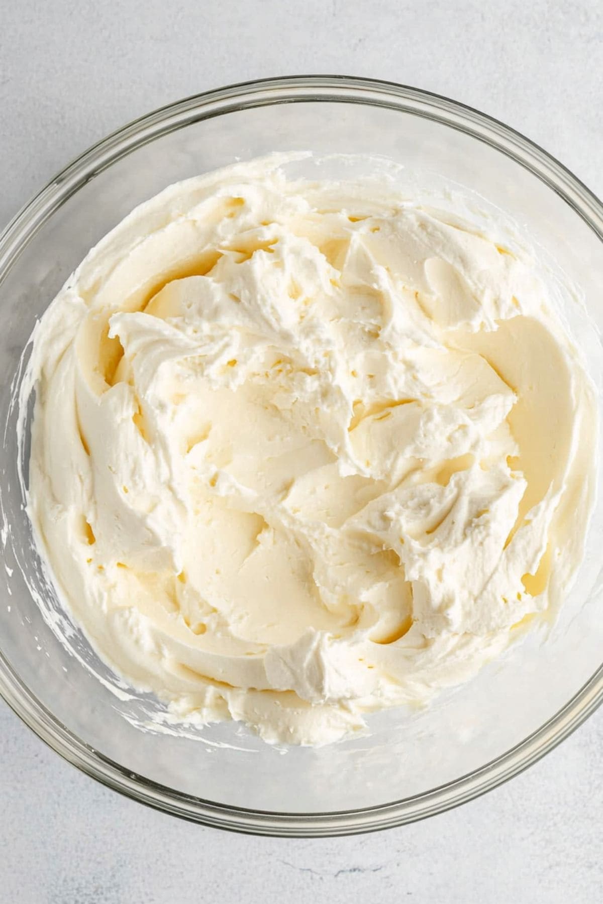 Cream cheese frosting in a glass mixing bowl, top view