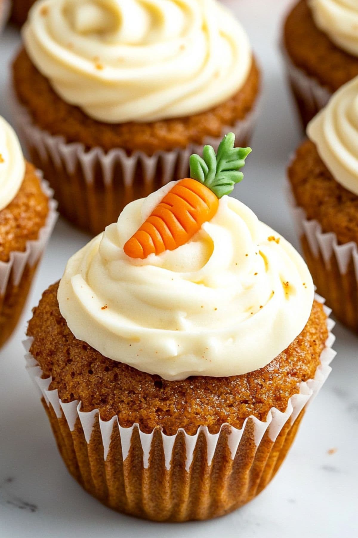 Carrot cake muffins topped with cream cheese frosting and carrot shaped candies, close up