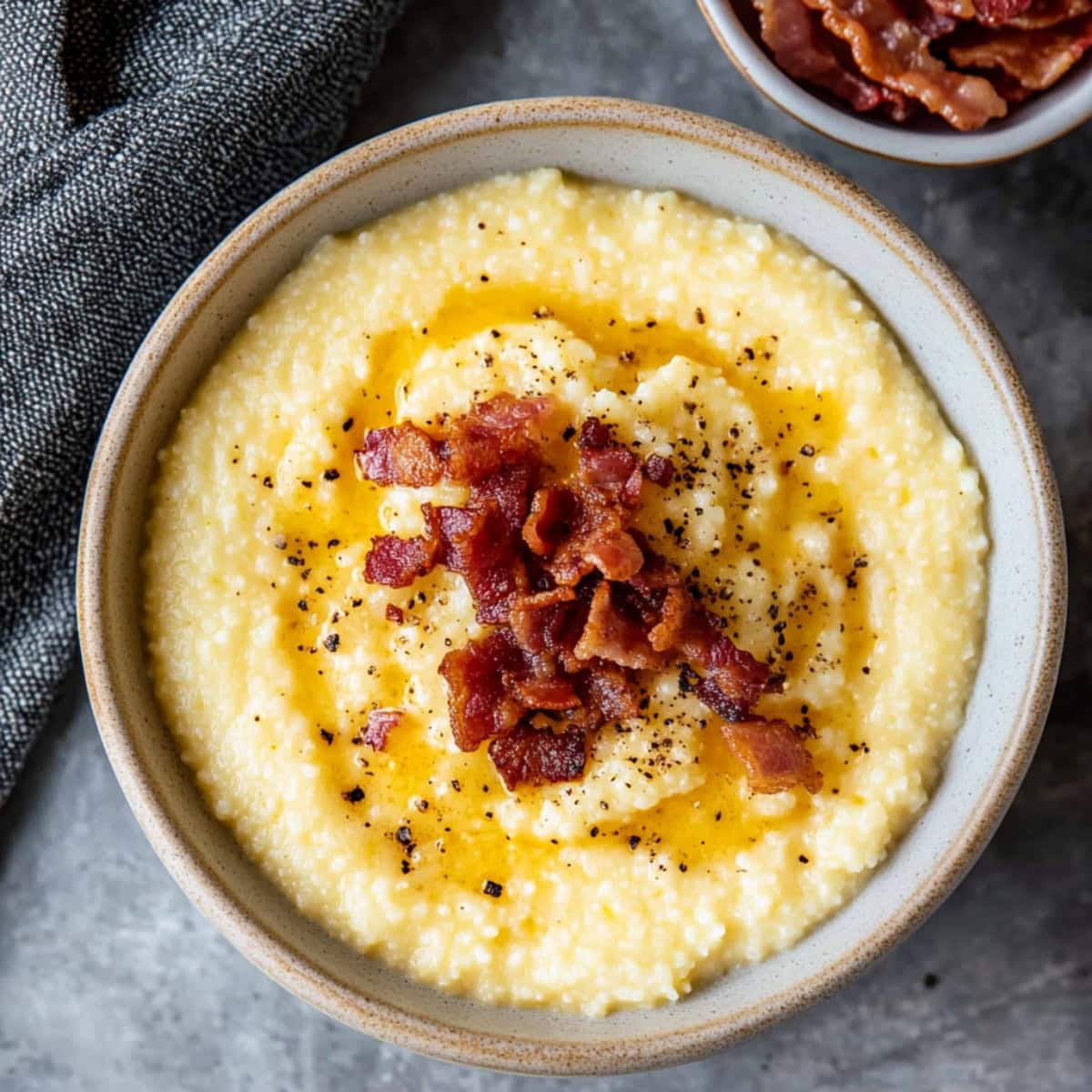 An overhead view of cheesy grits with bacon in a bowl.