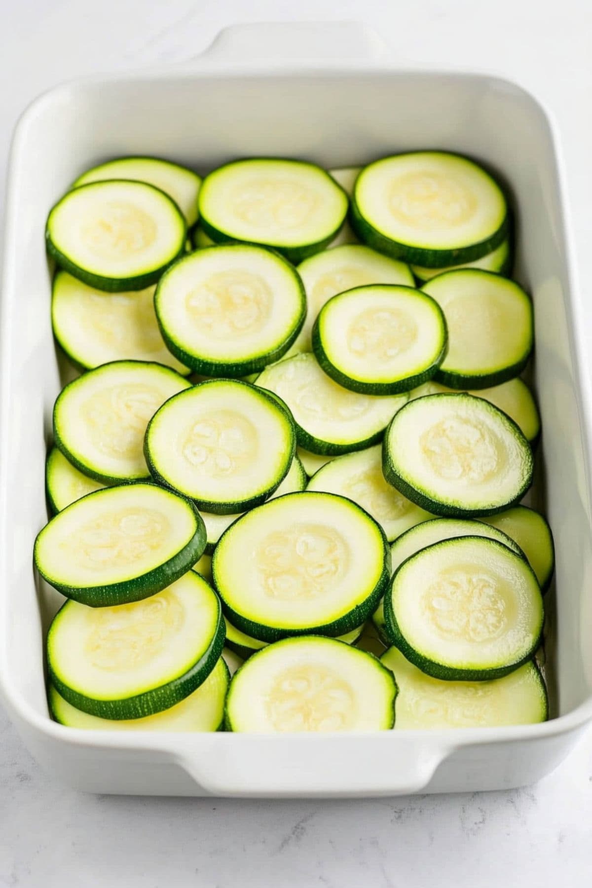 Sliced zucchini arranged in a baking dish.