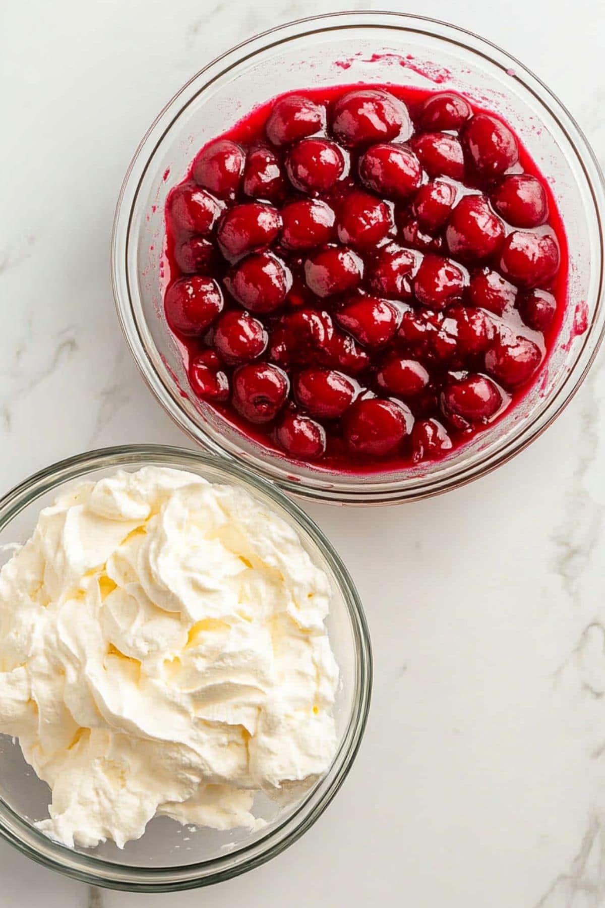 Cherry pie filling and cream cheese in separate glass bowls.