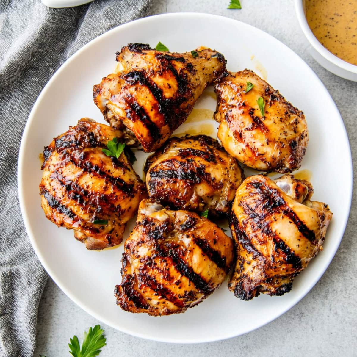 Grilled boneless skinless chicken thighs in a white plate.