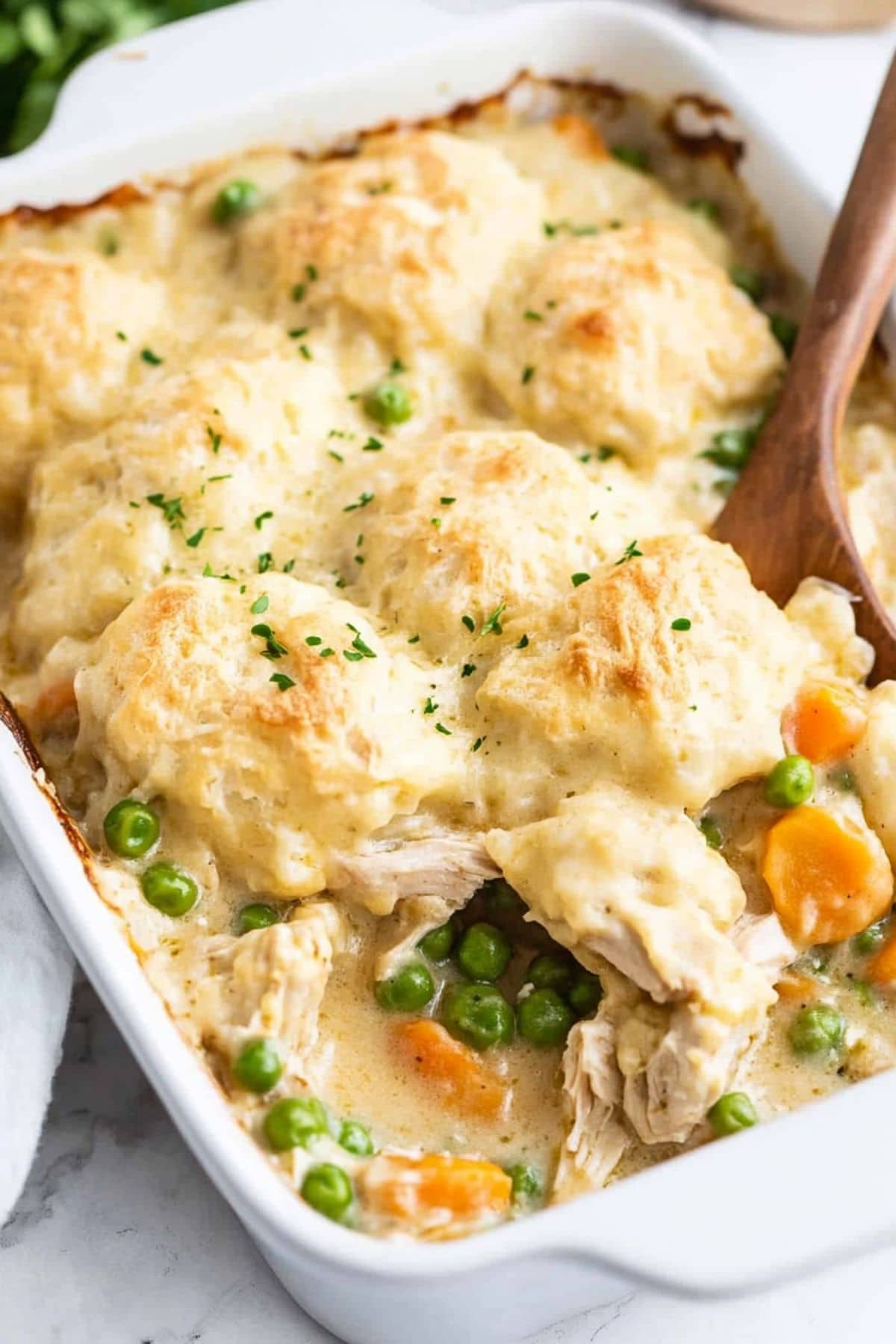 Wooden spoon dipped on chicken and dumplings casserole dish. 