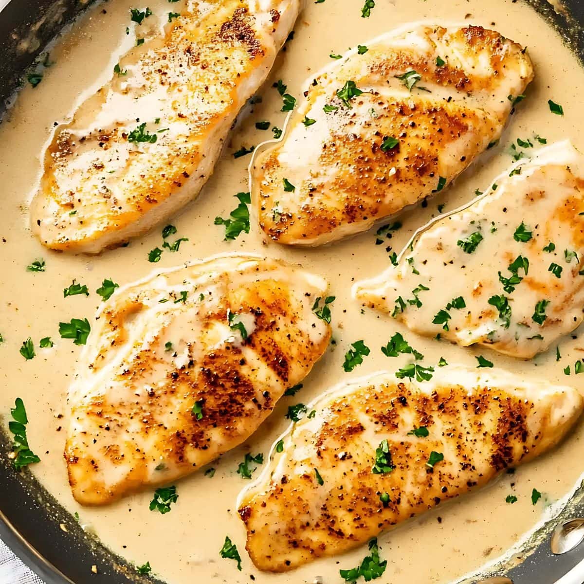 Seared chicken breast with cream cheese sauce in a skillet.