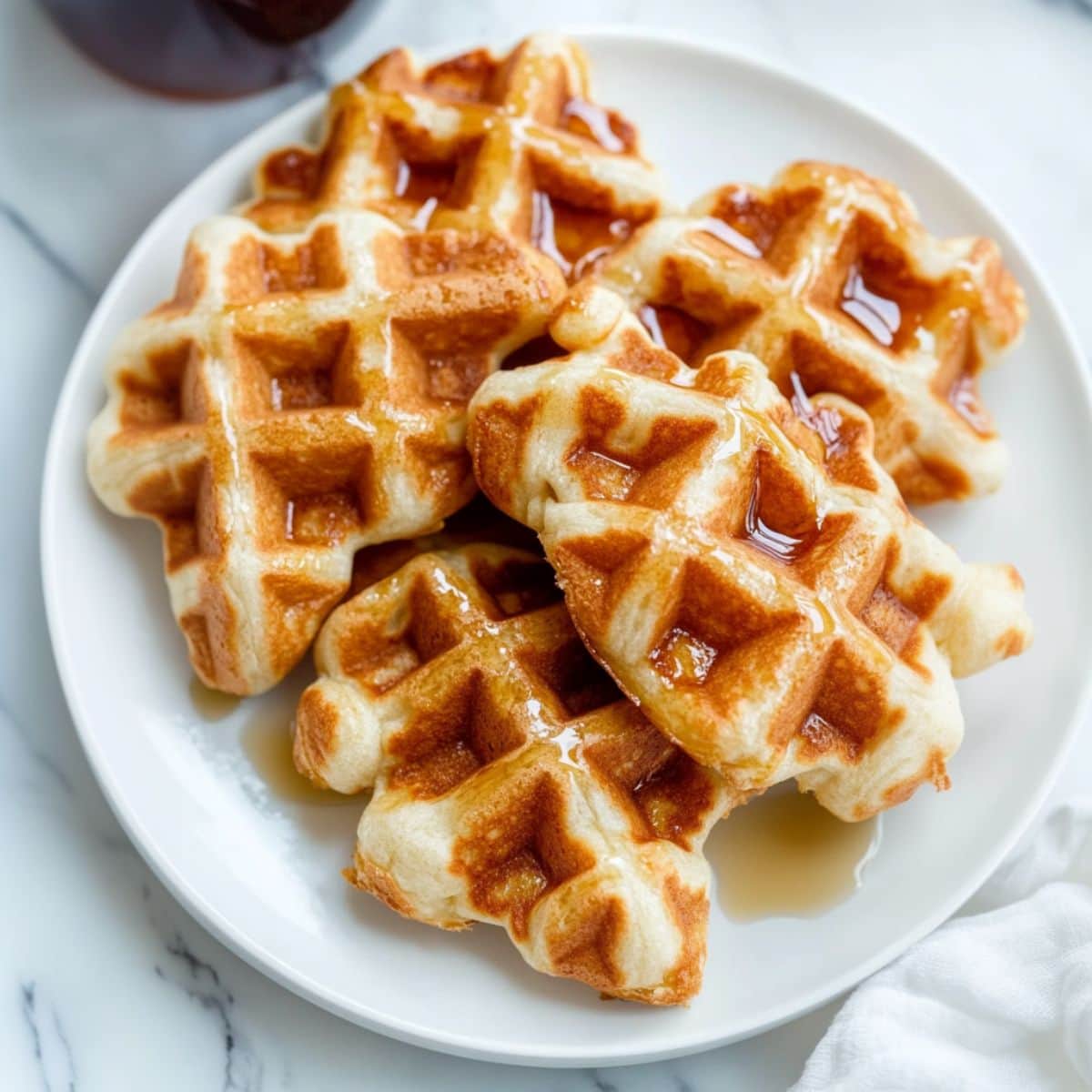 Croffles on a white plate drizzled with maple syrup, top view