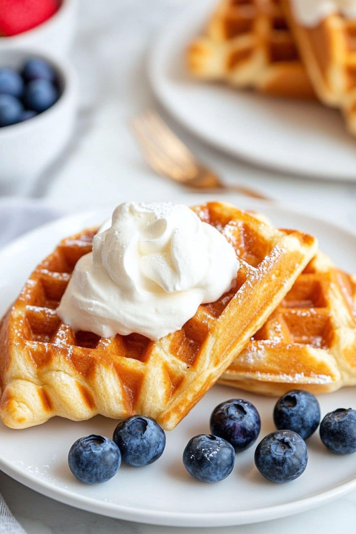 Croffle served on a white plate garnished with whipped cream and blueberries.