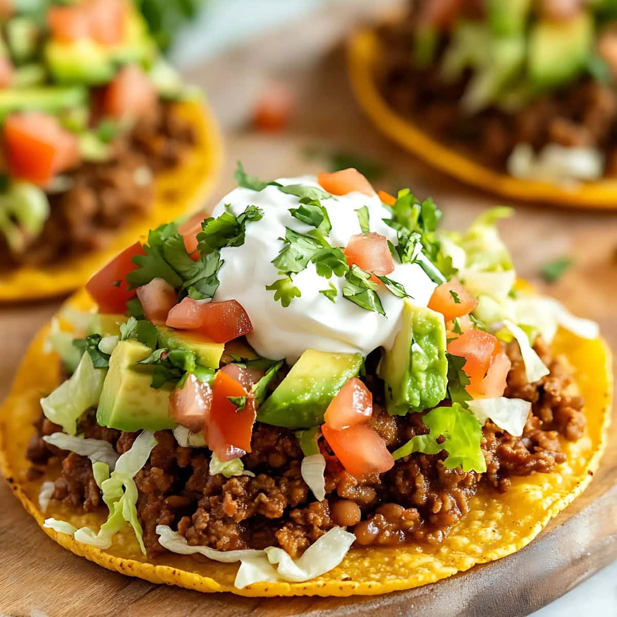 Ground Beef Tostadas with tomatoes, sour cream, avocado, and fresh cilantro.