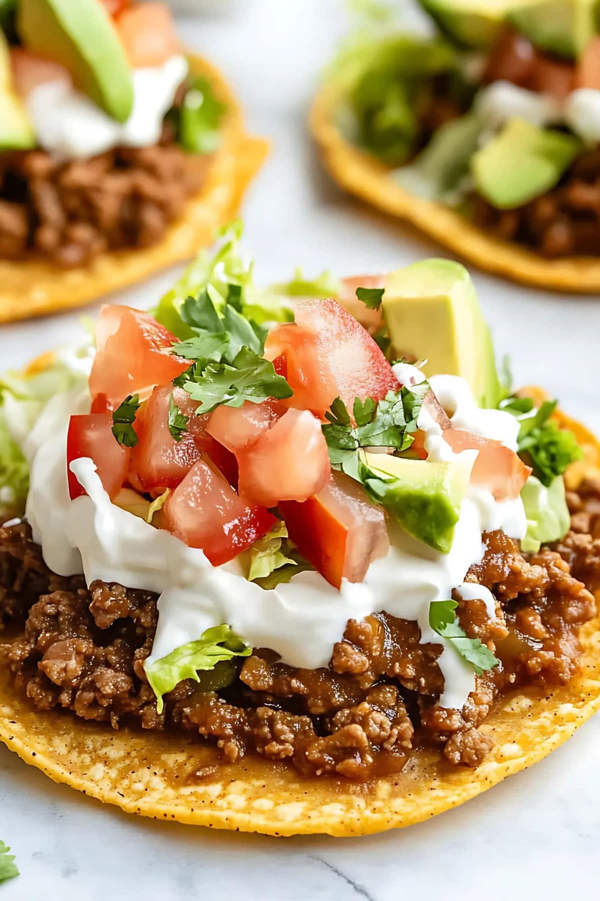 Tostadas with seasoned ground beef, beans , fresh salsa, and avocado, close up