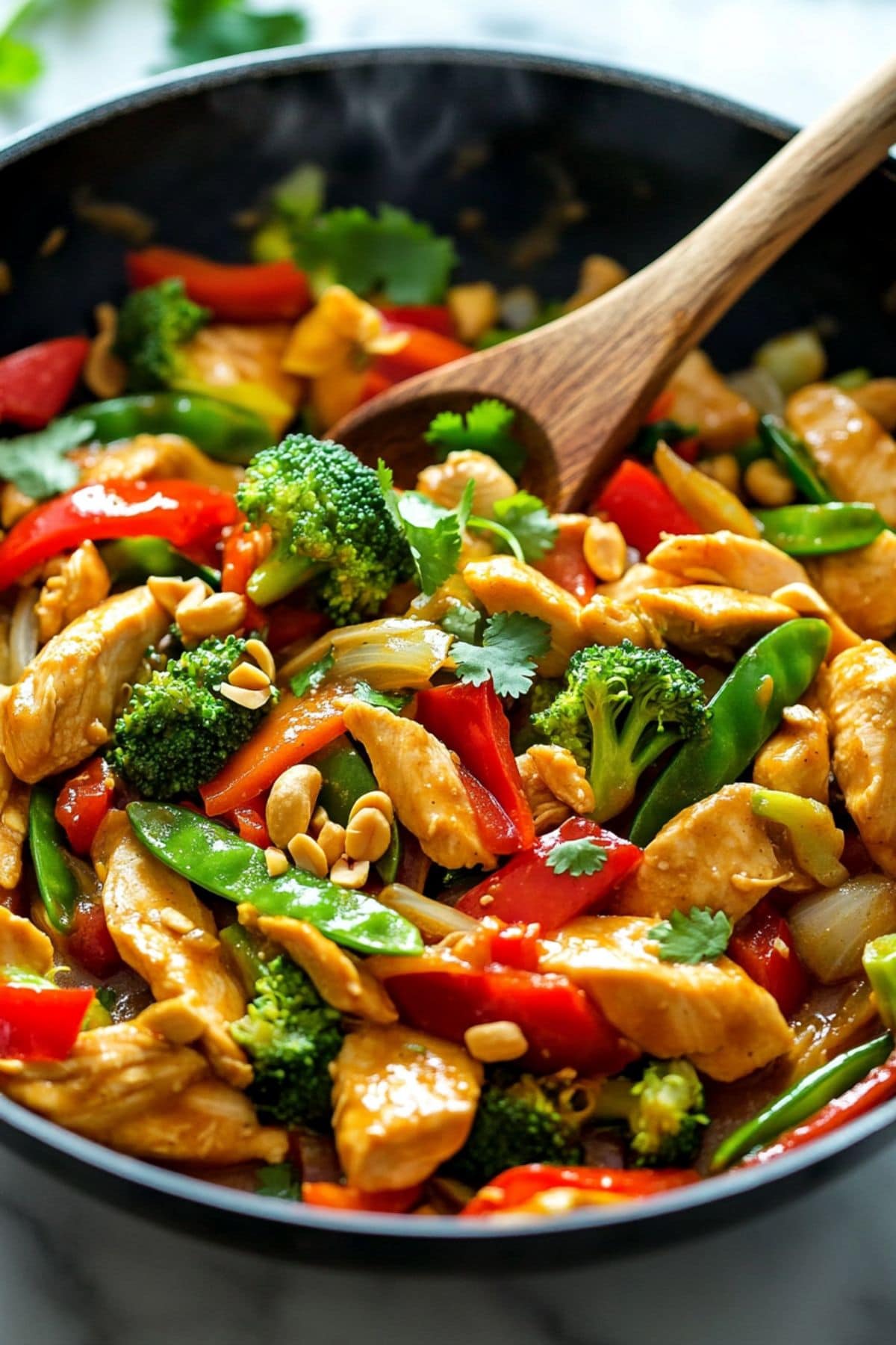 Peanut Satay Chicken Stir Fry with broccoli, bell peppers chopped peanuts and cabbage tossed in peanut satay sauce in a wok pan, close up