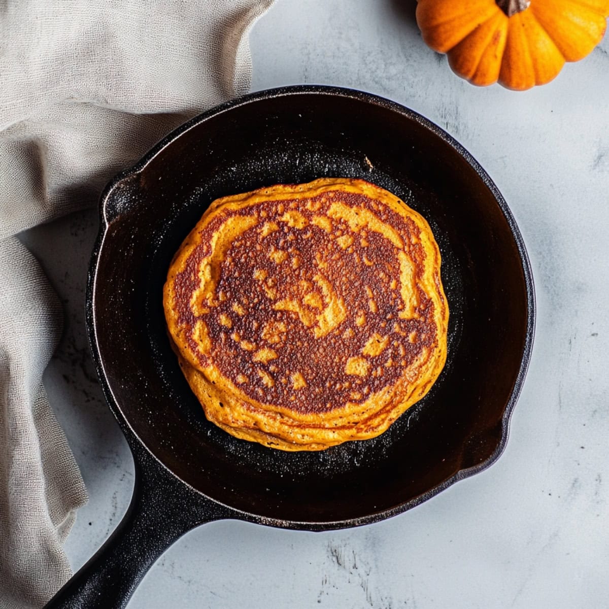 A skillet with a pumpkin spice pancake, overhead view.