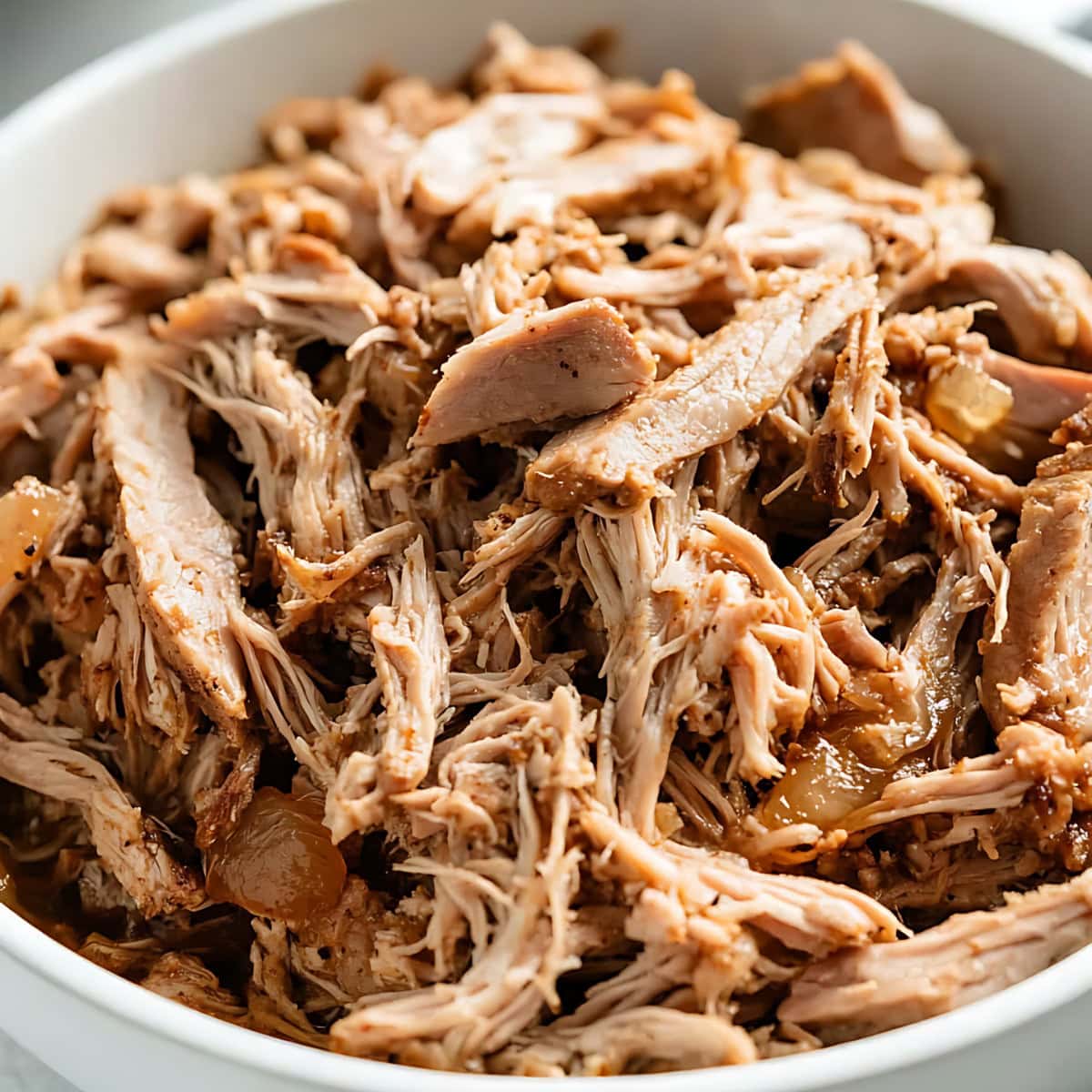 Pulled pork served in a white bowl.