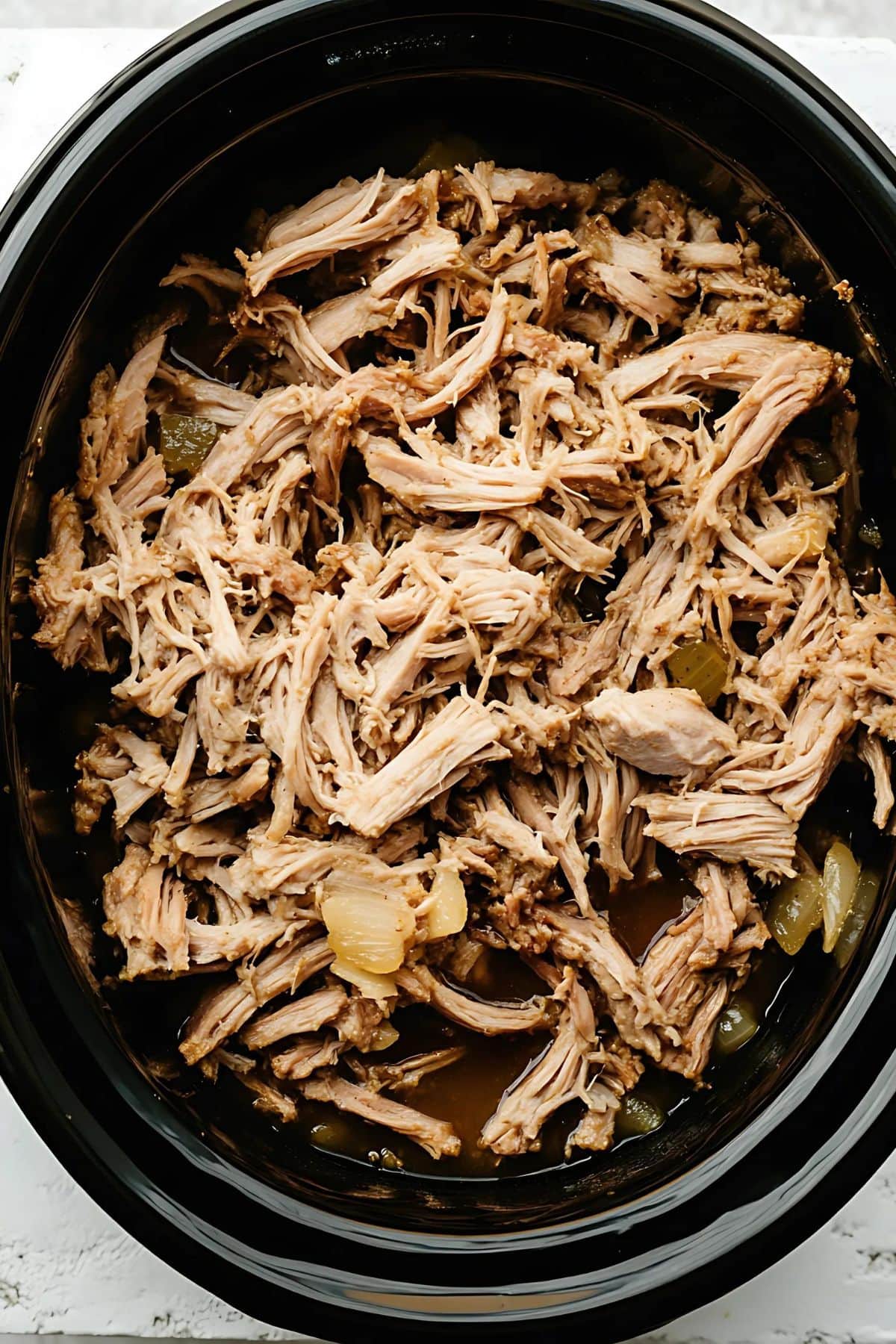 Slow cooker pot with pulled pork inside.