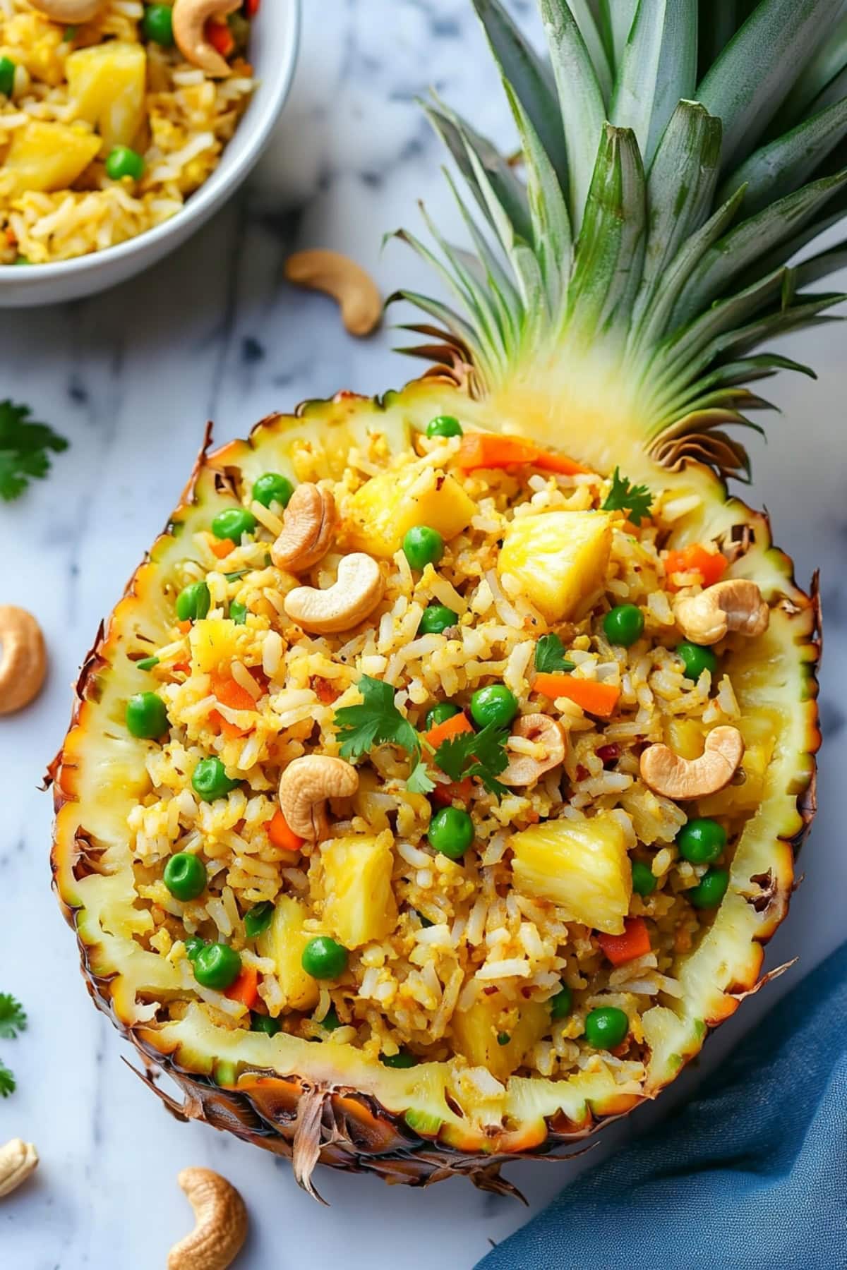 Fried rice with pineapple, peas, and carrots served in a hollowed out pineapple garnished with cashews.