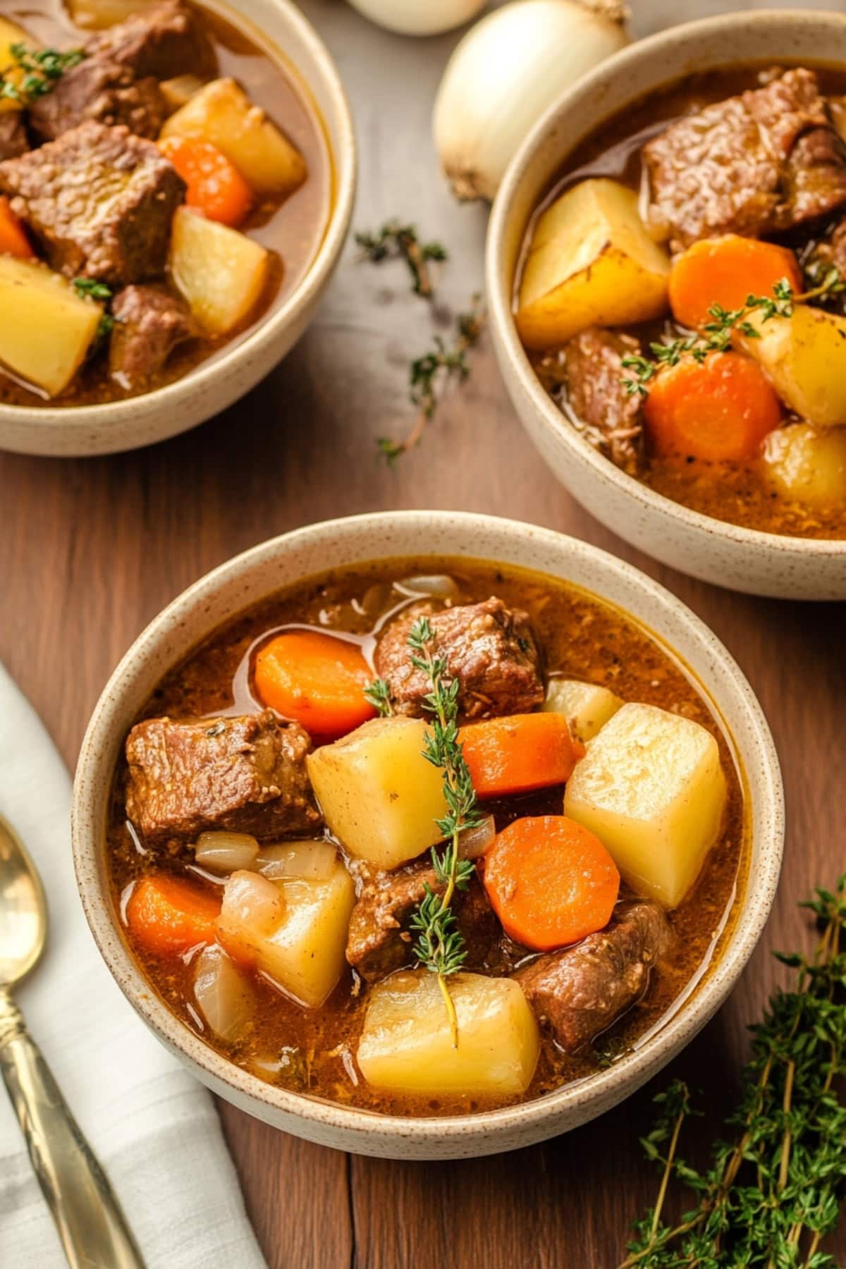 A warm bowl of apple cider beef stew with tender chunks of meat, carrots, potatoes, and a rich, savory broth.