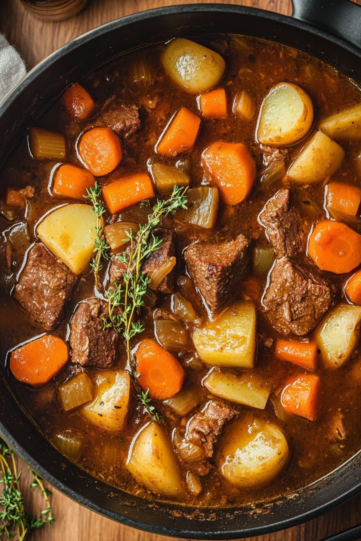 An overhead view of apple cider beef stew with veggies and thyme.