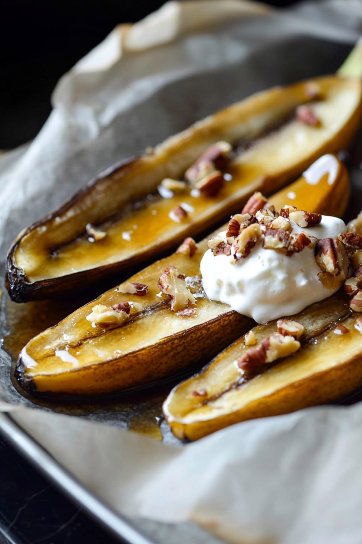 Close-up of baked bananas topped with nuts and ice cream