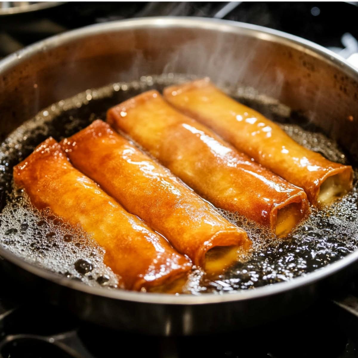 Banana lumpia cooked in hot oil in a skillet