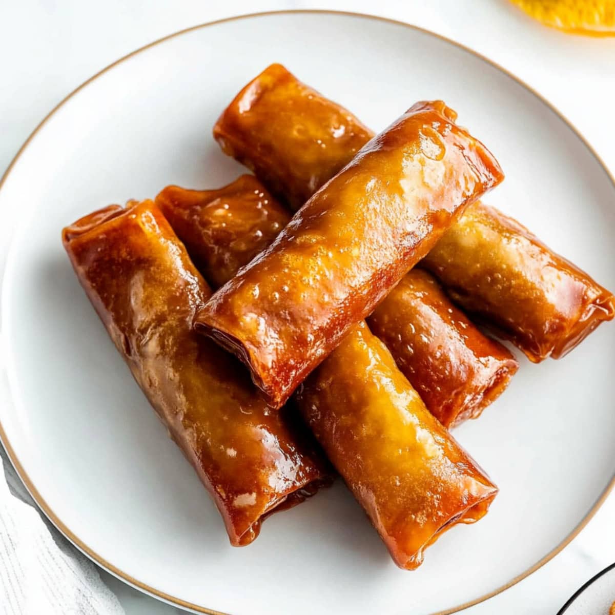 An overhead view of banana lumpia stacked on a plate