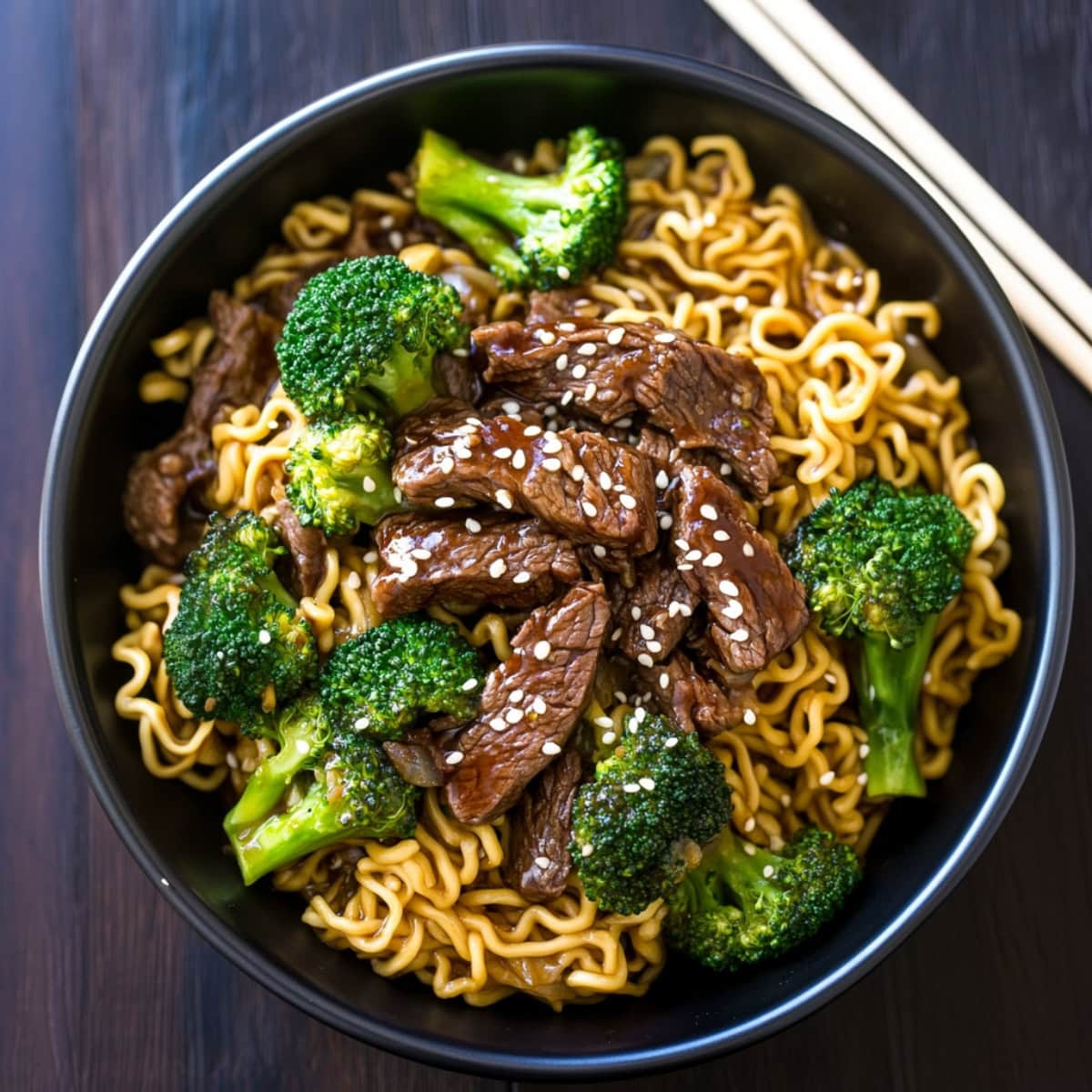 Stir fried beef and broccoli ramen in a blow bowl garnished with sesame seeds. 