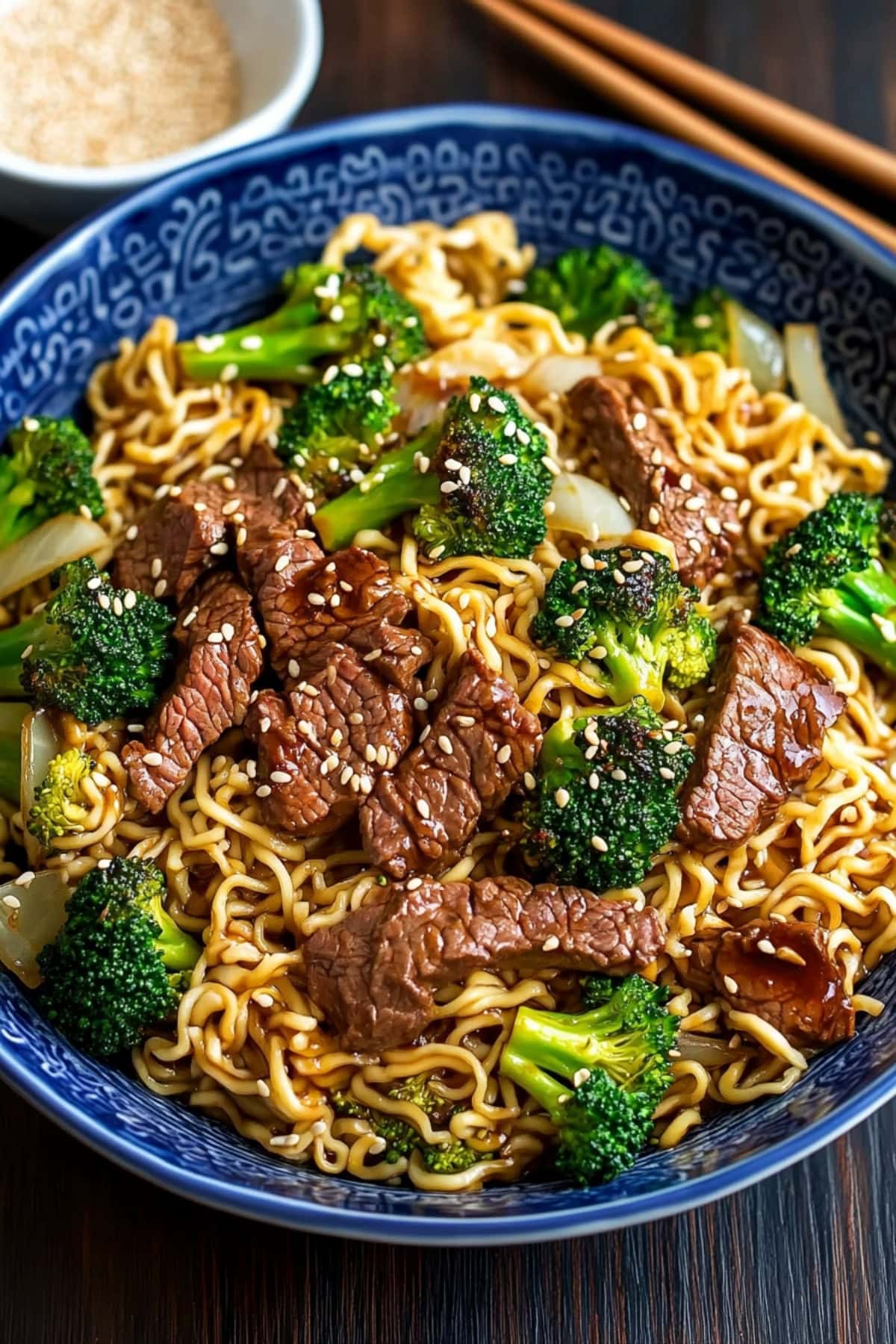 Bowl of stir fried beef and broccoli ramen in a blue bowl.