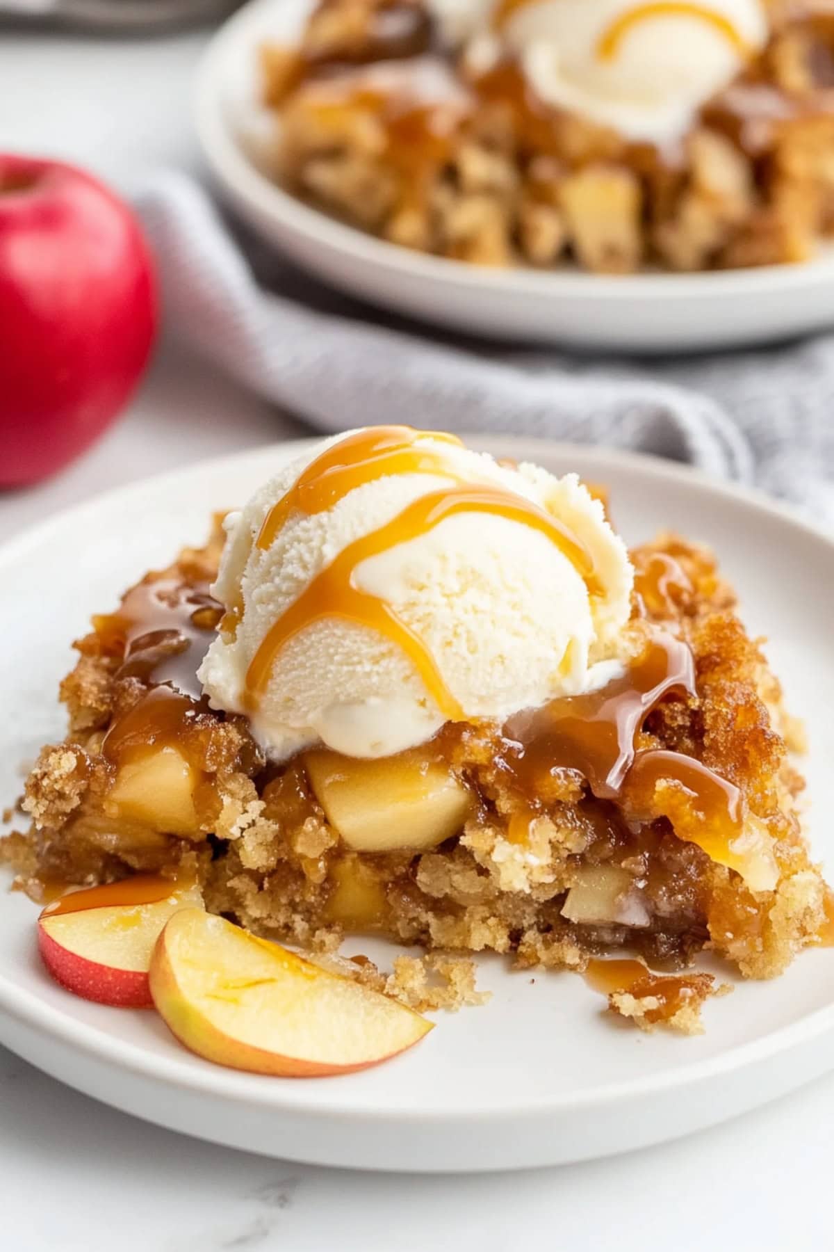 Two servings of caramel apple dump cake in a plate garnished with vanilla ice cream, drizzled with caramel syrup.