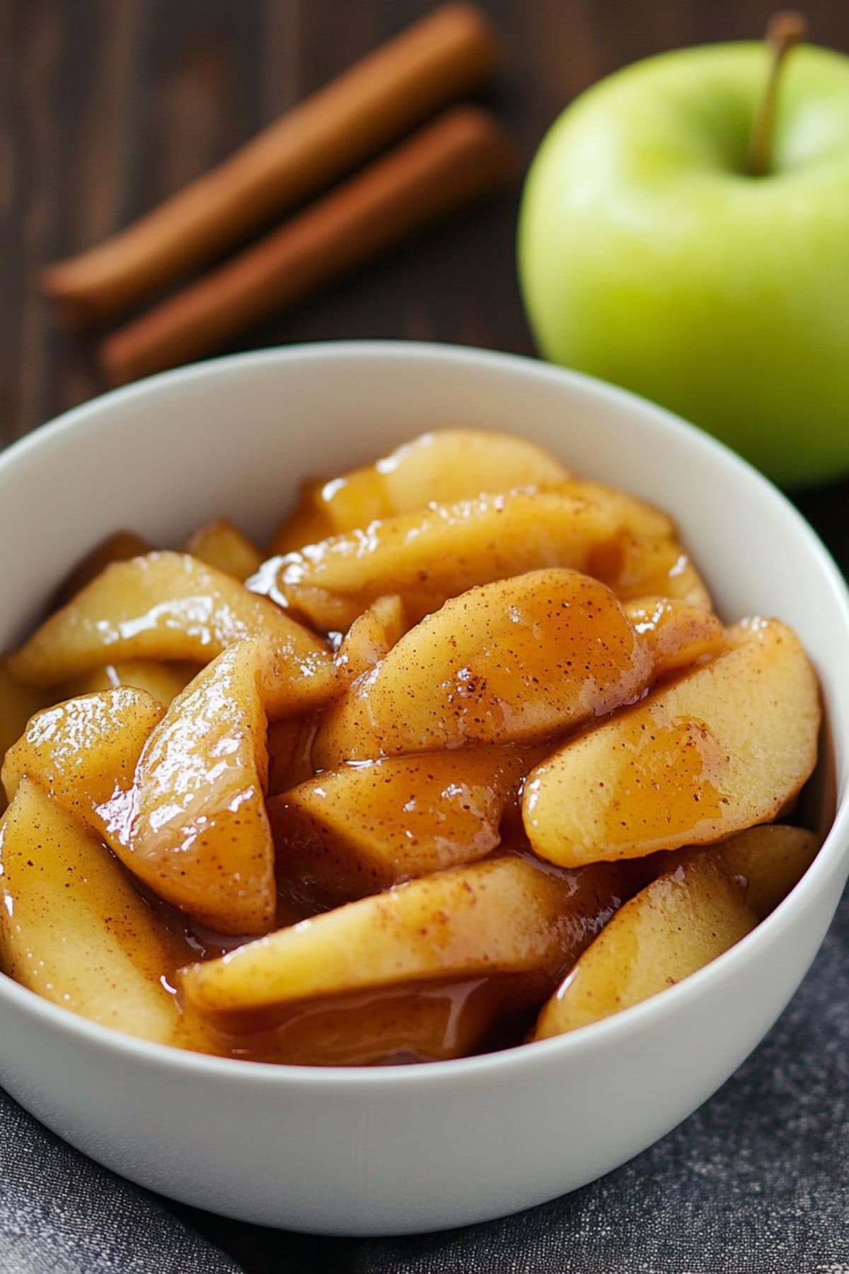 Sliced caramelized apple with sauce served in a white bowl.