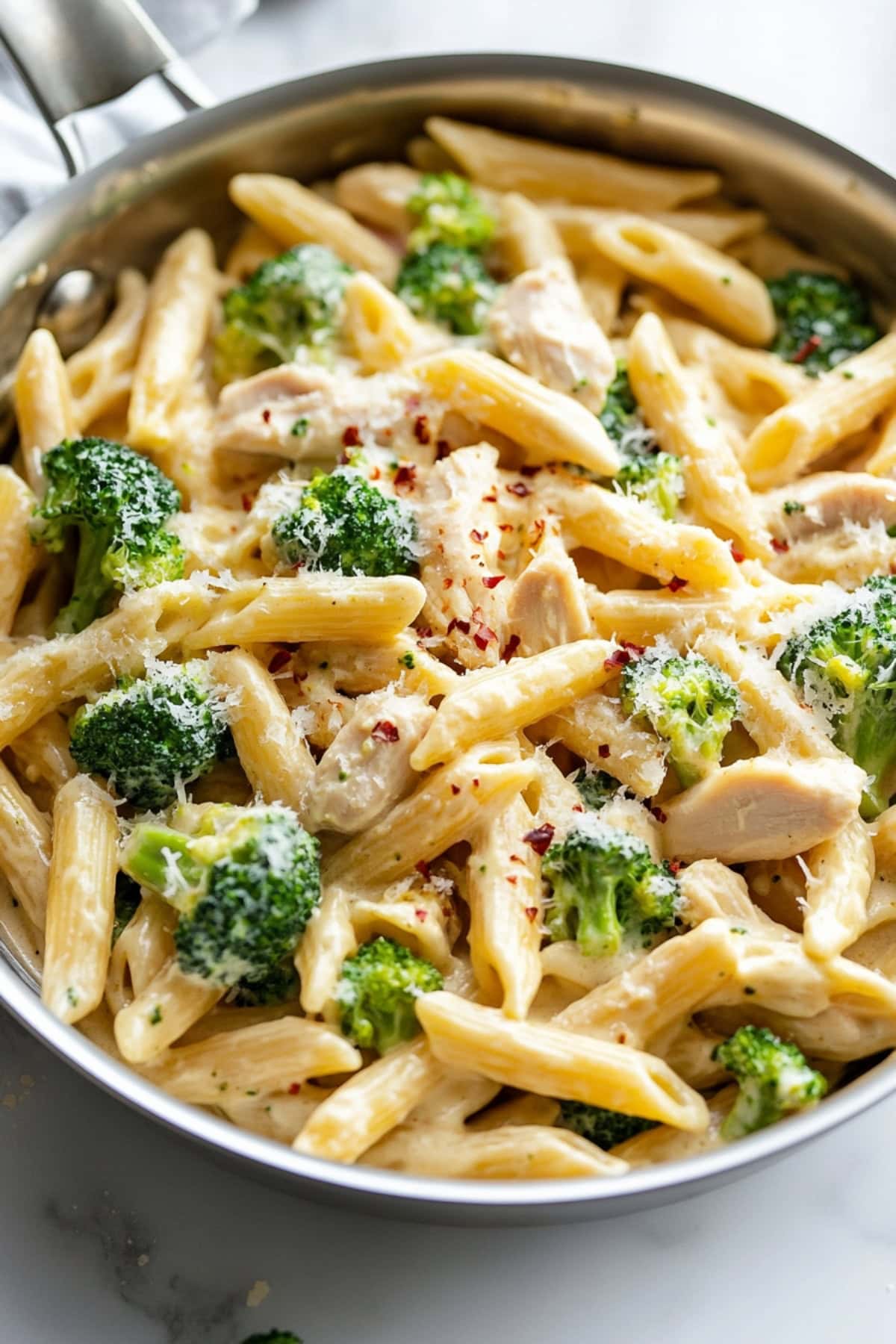 An overhead view of chicken and broccoli pasta in a skillet.