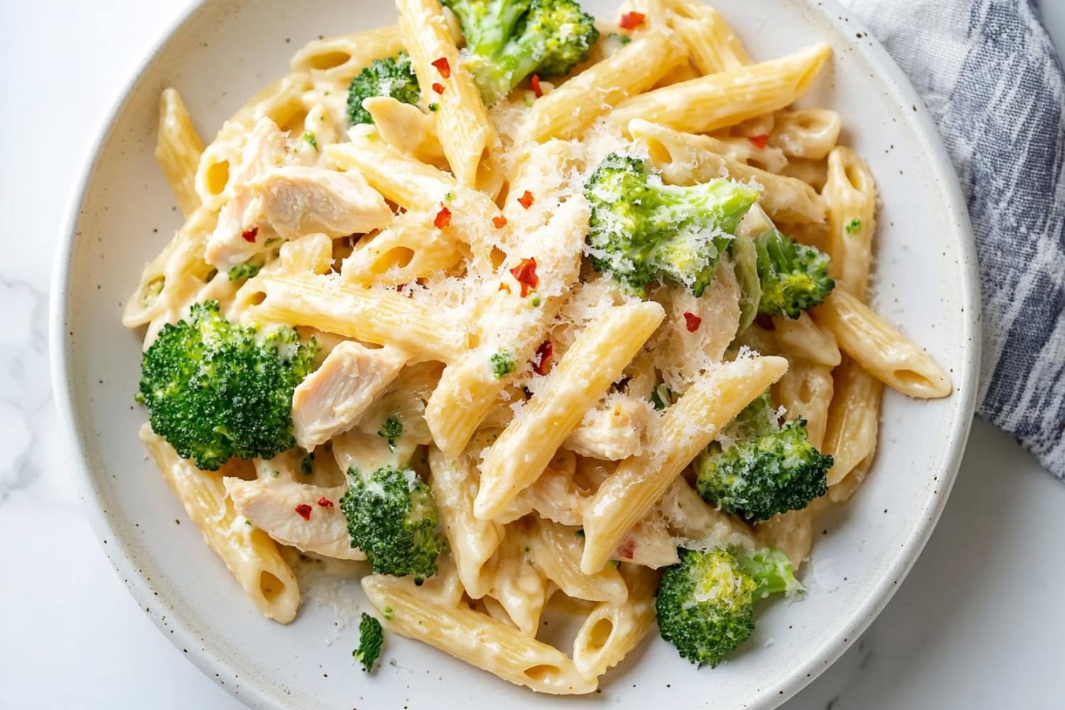 An overhead view of a plate of chicken and broccoli pasta.