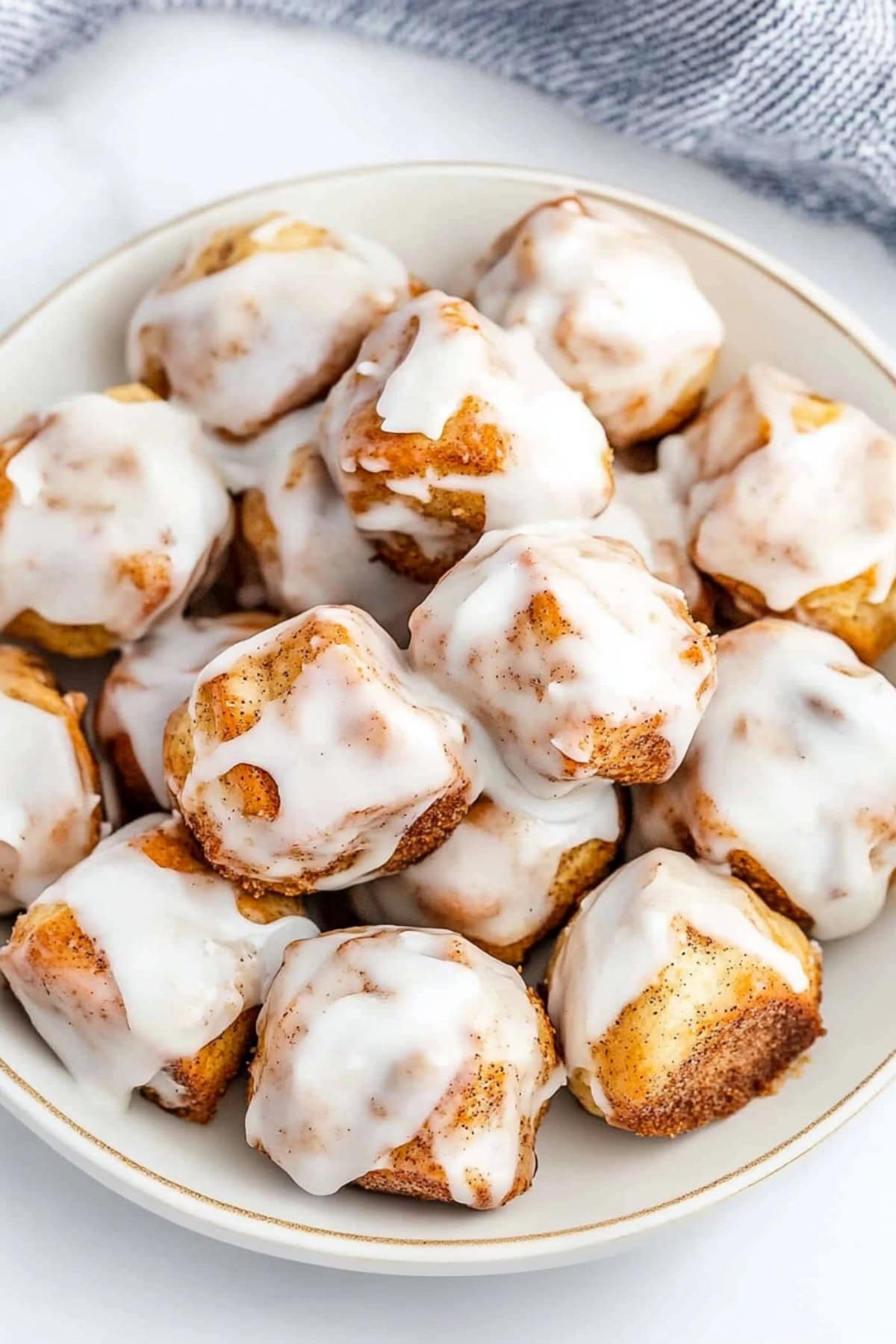 Bowl full of cinnamon roll bites with white glaze, top view