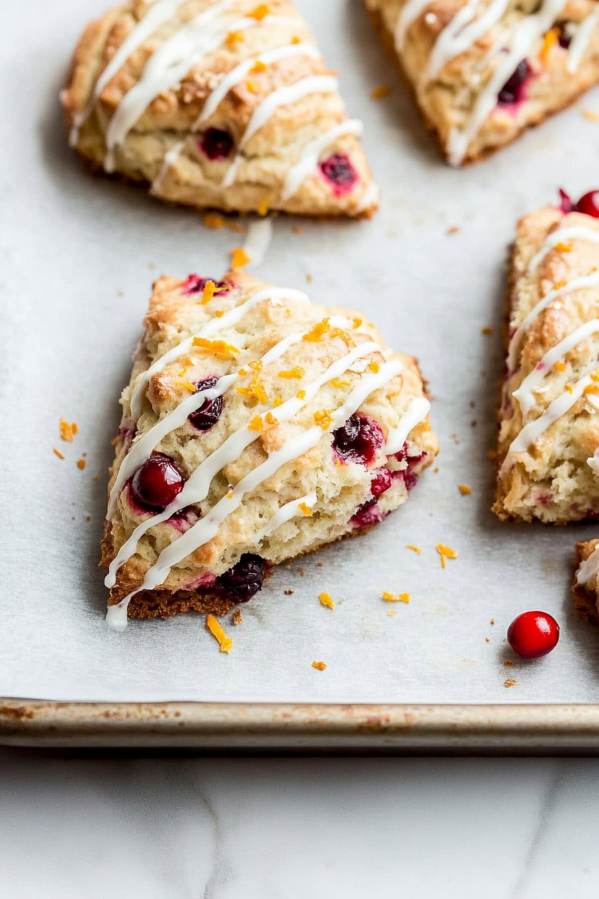 Homemade cranberry orange scones  drizzled with glaze on a baking pan, close up