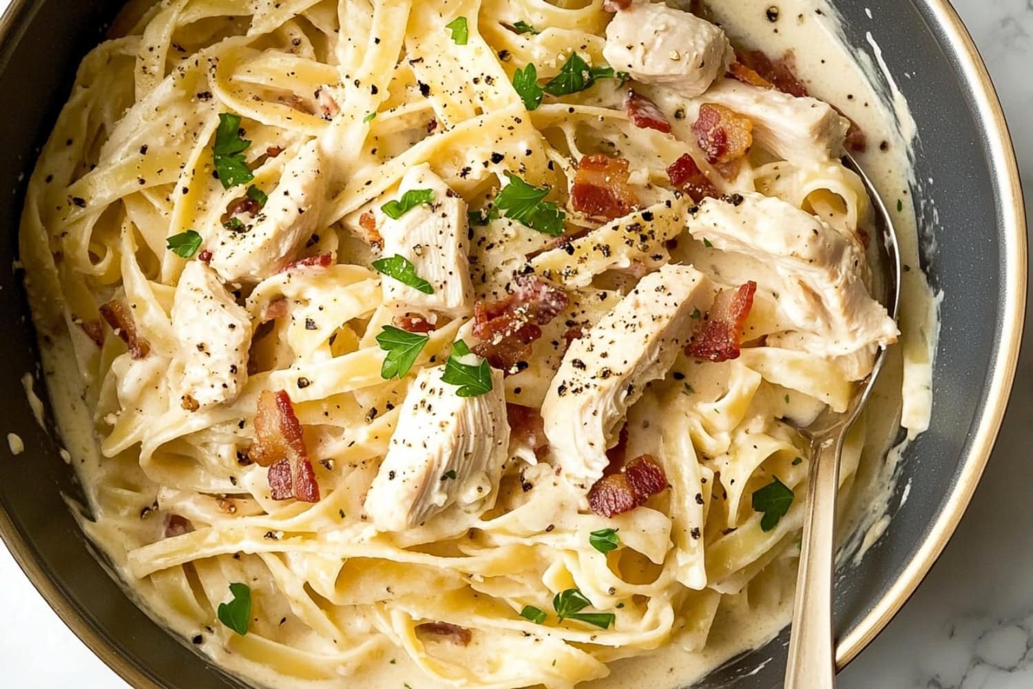 Close-up of creamy pasta, showcasing the savory combination of chicken, bacon, and creamy sauce.