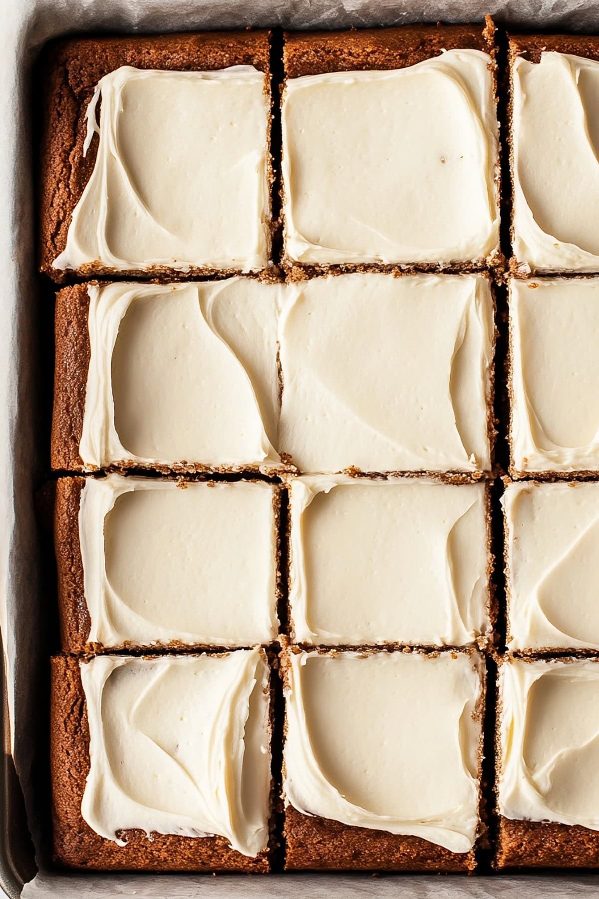 Overhead view of gingerbread sheet  cake with cream cheese frosting in a baking pan.