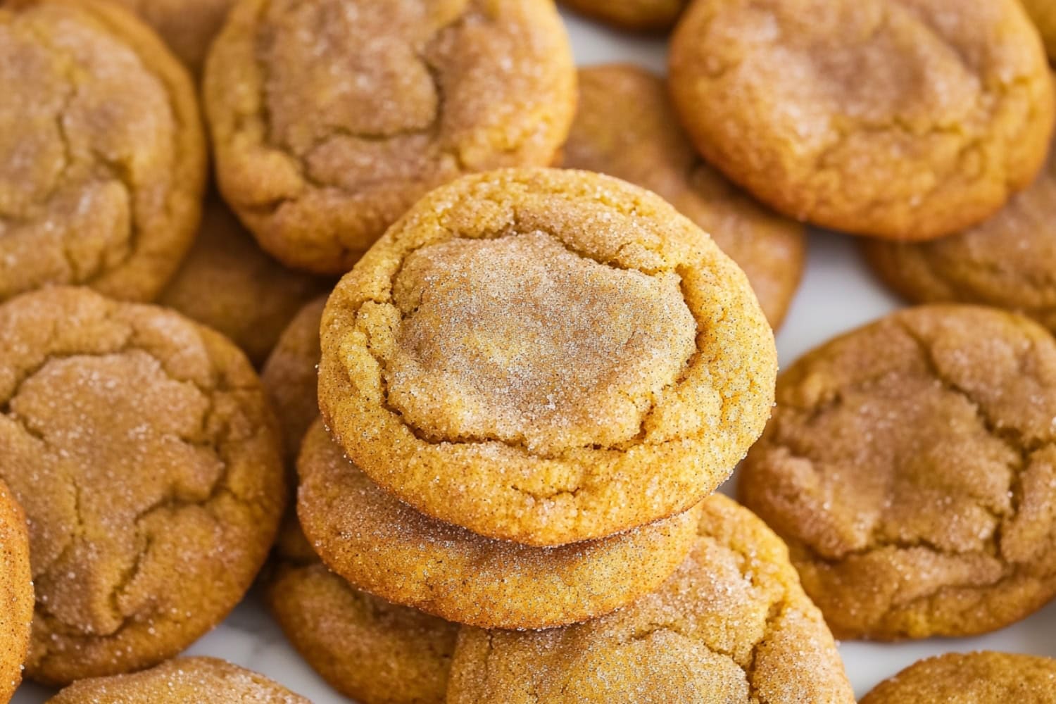 A festive autumn display of pumpkin snickerdoodle cookies on a white marble table.