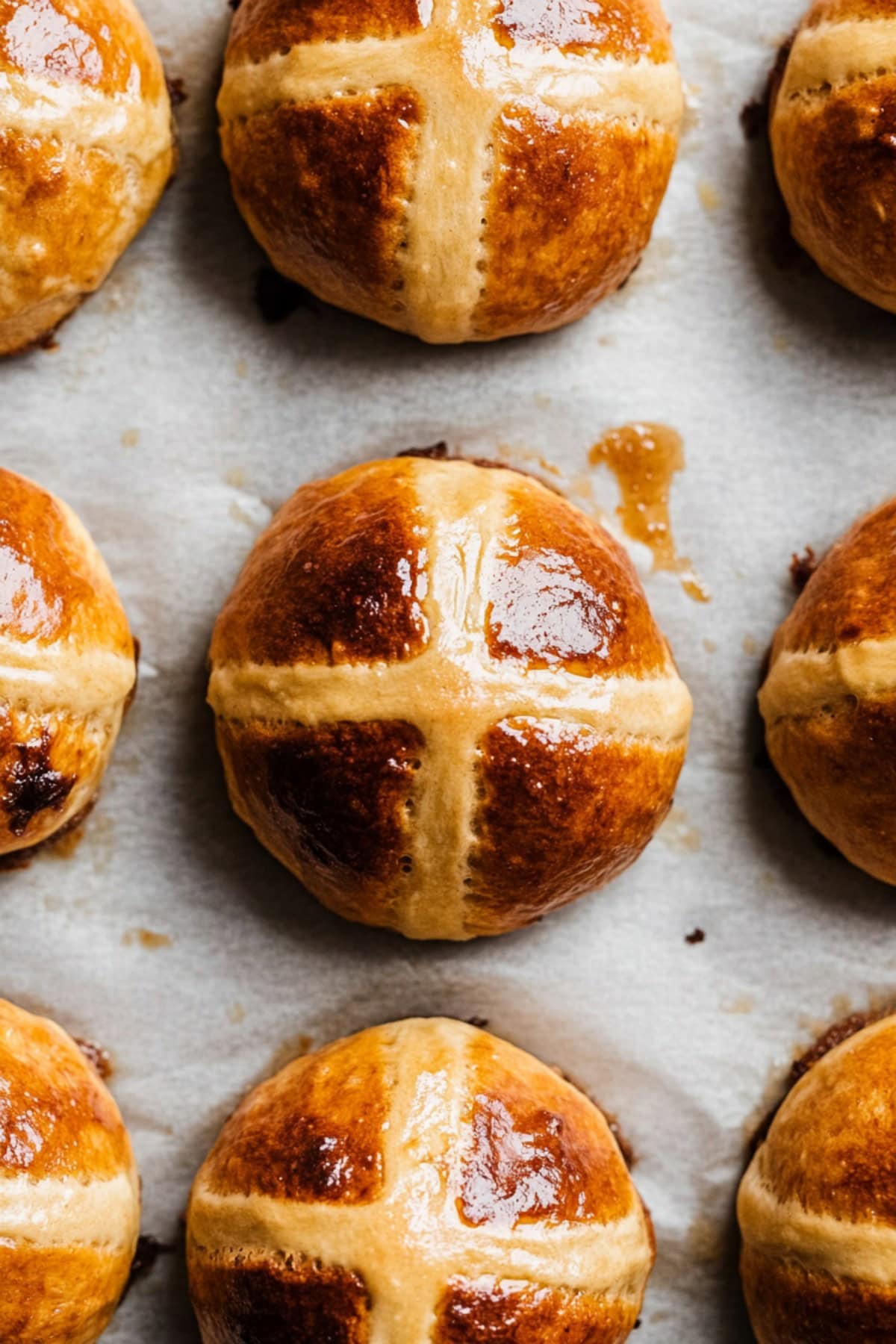 An overhead view of hot cross buns on parchment paper.