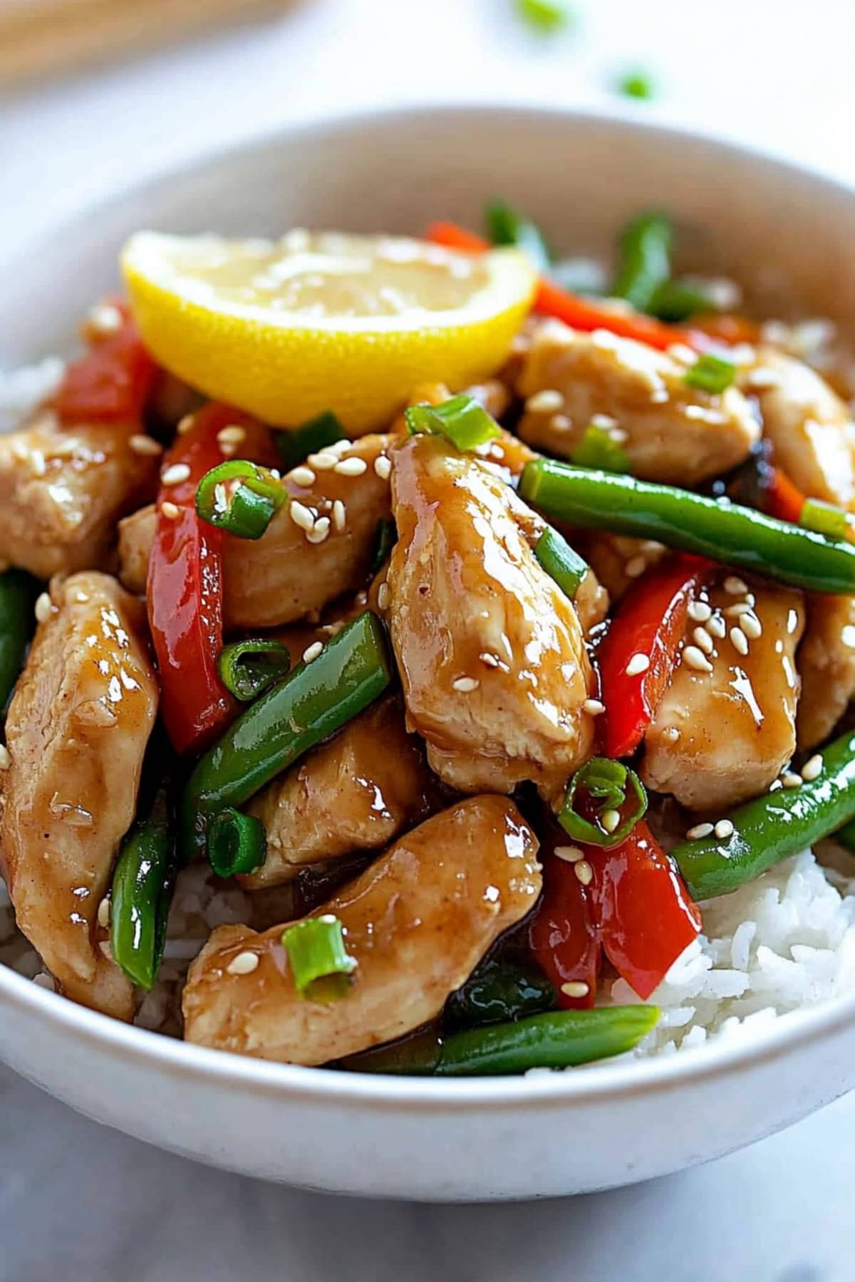 Lemon chicken stir-fry with veggies served in a white bowl.