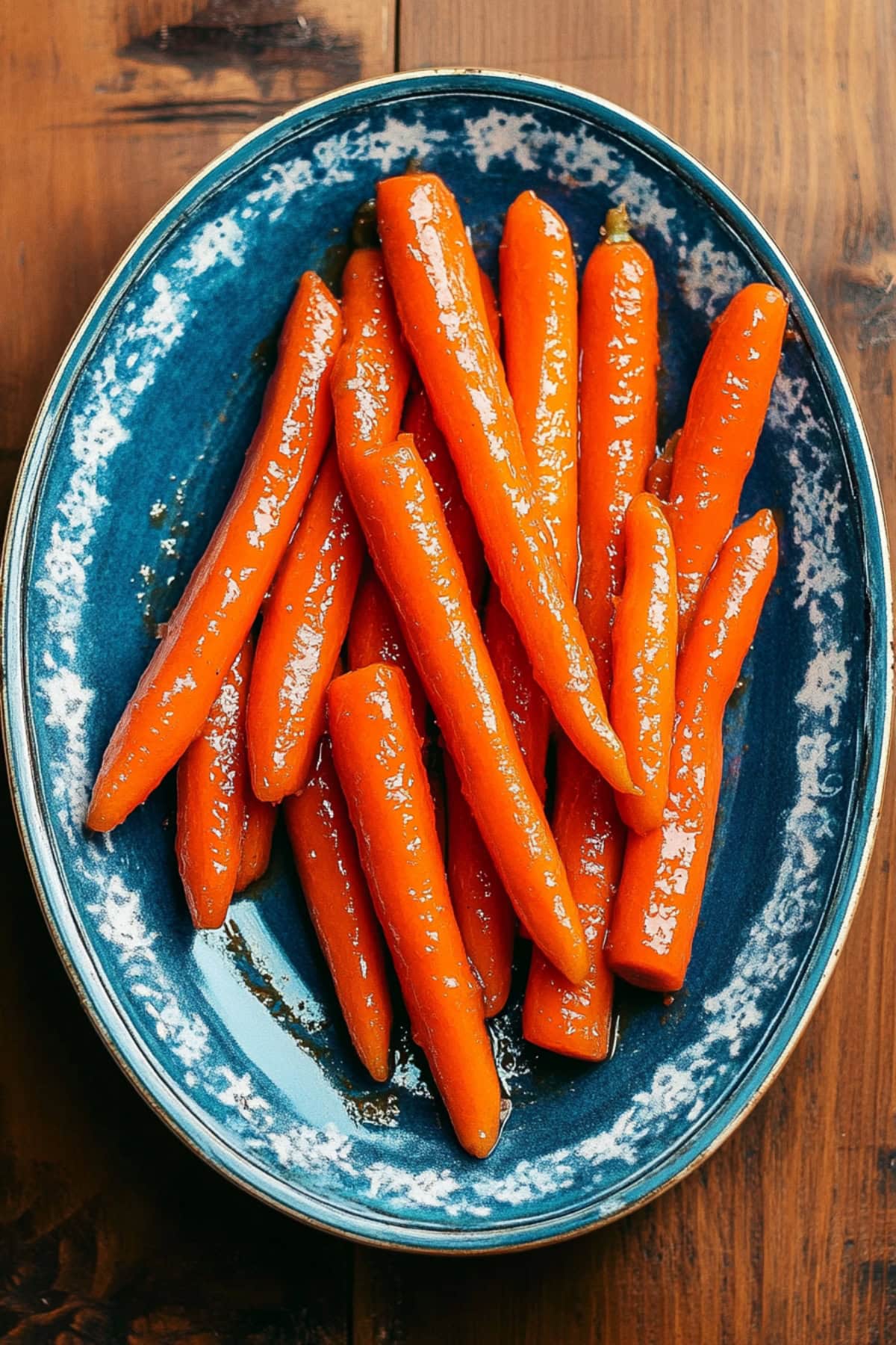 Caramelized maple glazed carrots resting on a blue platter.