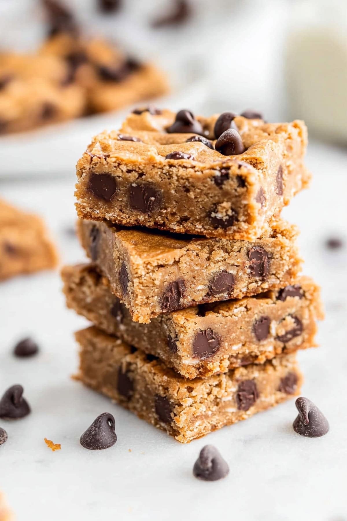 Stacked peanut butter chocolate chip bars on a white marble table.