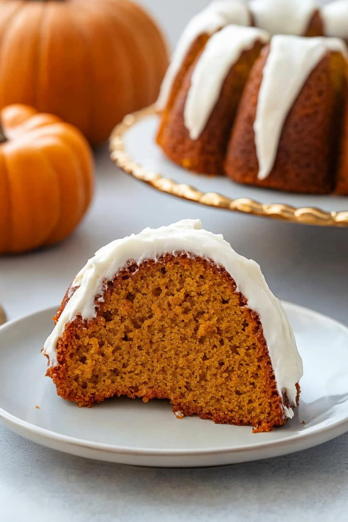 Slice portion of pumpkin bundt cake with white glaze on top.