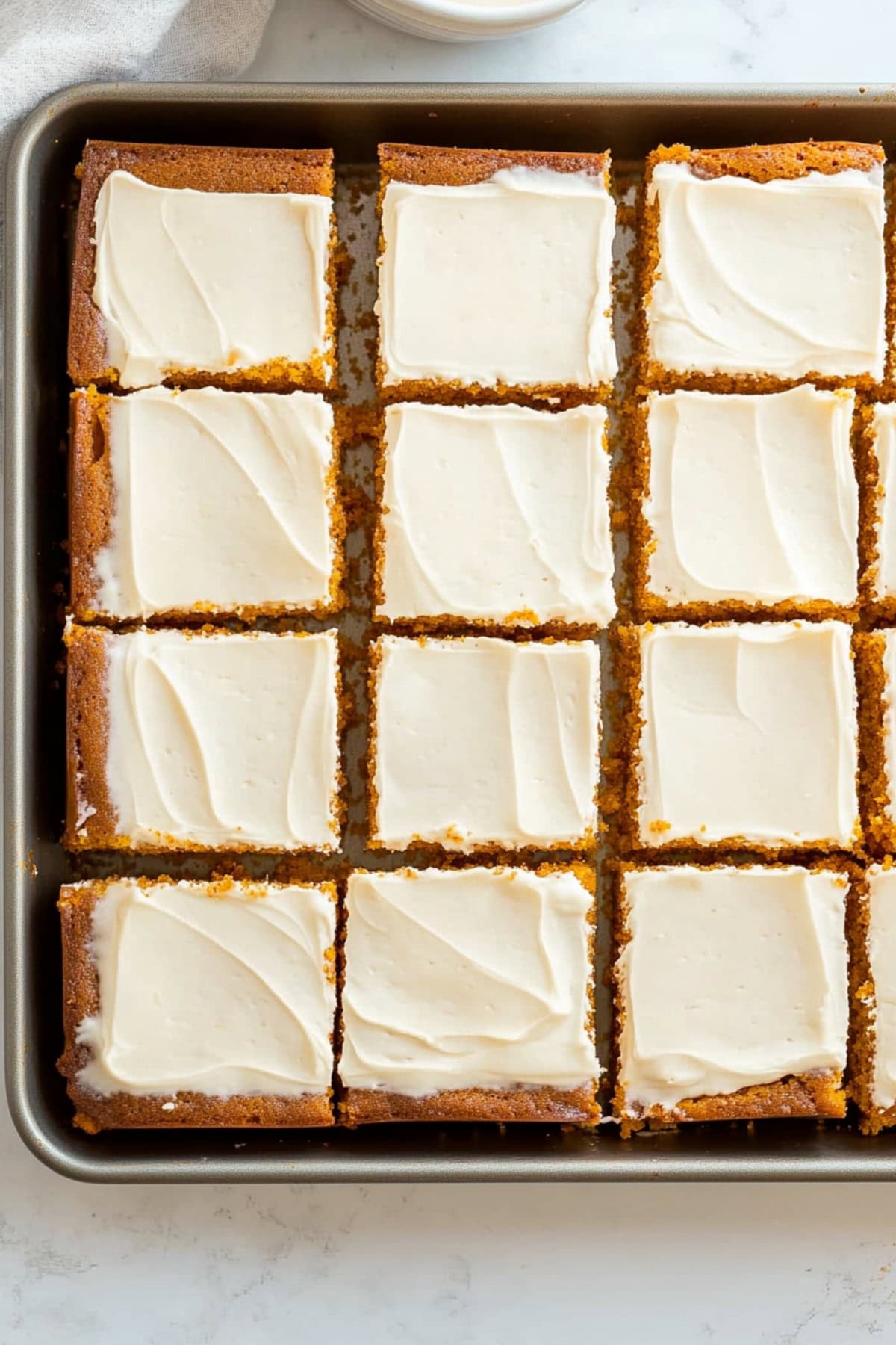 A baking pan of fluffy pumpkin cake with cream cheese frosting.