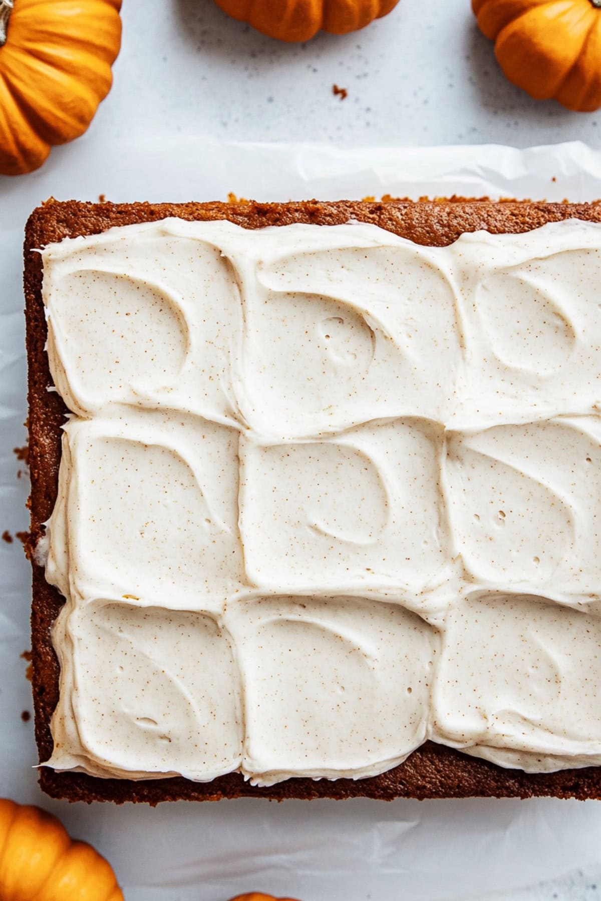 Whole pumpkin cake with ground cinnamon on a white marble table, top view.