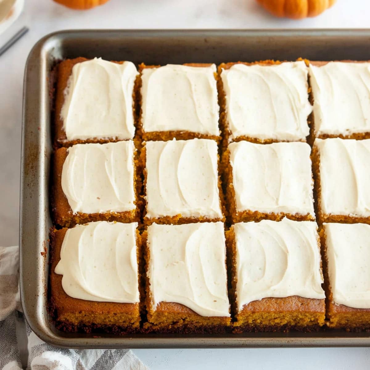 Moist pumpkin cake with cream cheese frosting in a baking pan.